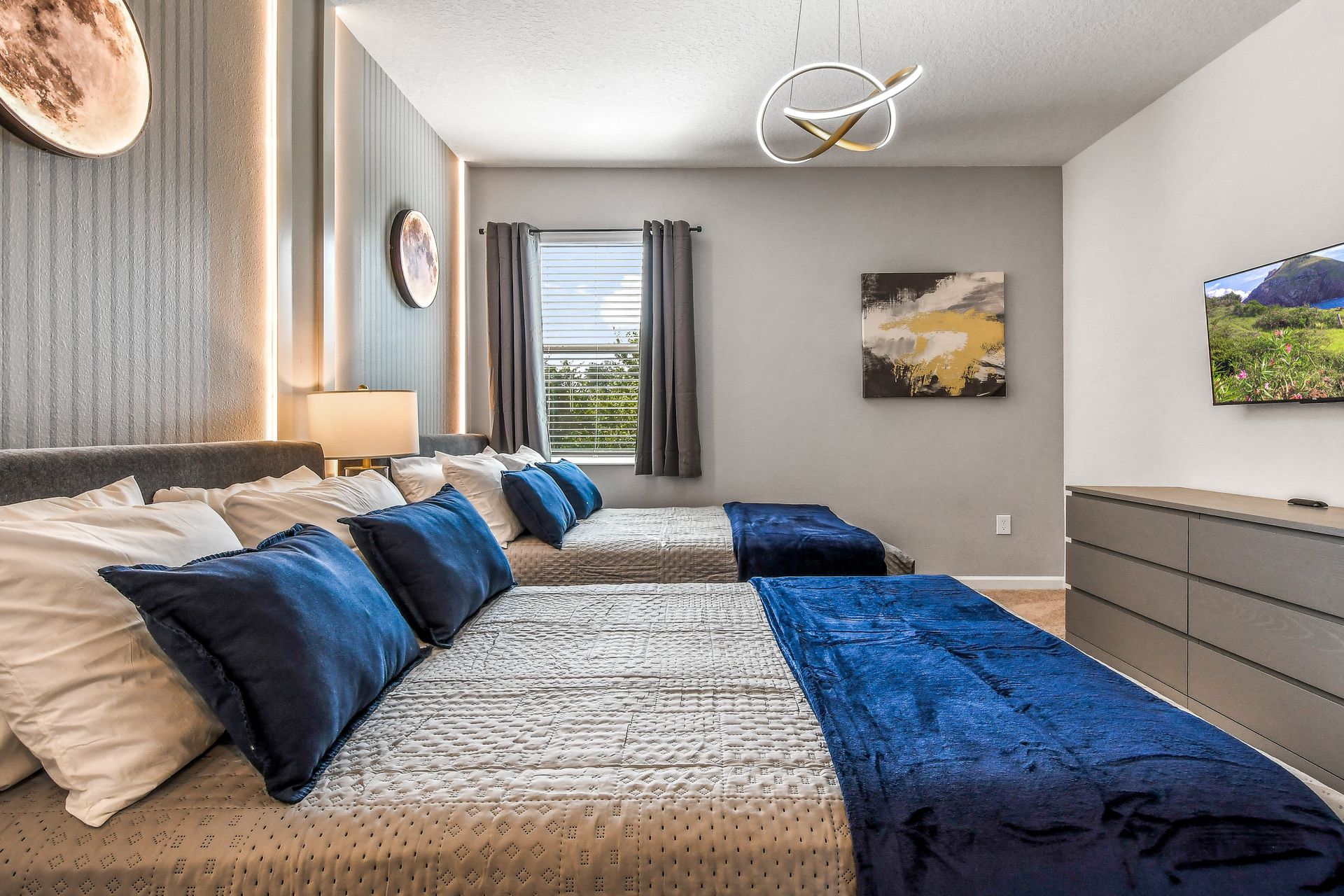 Sophisticated bedroom with double beds, celestial decor, blue accents, and natural light.