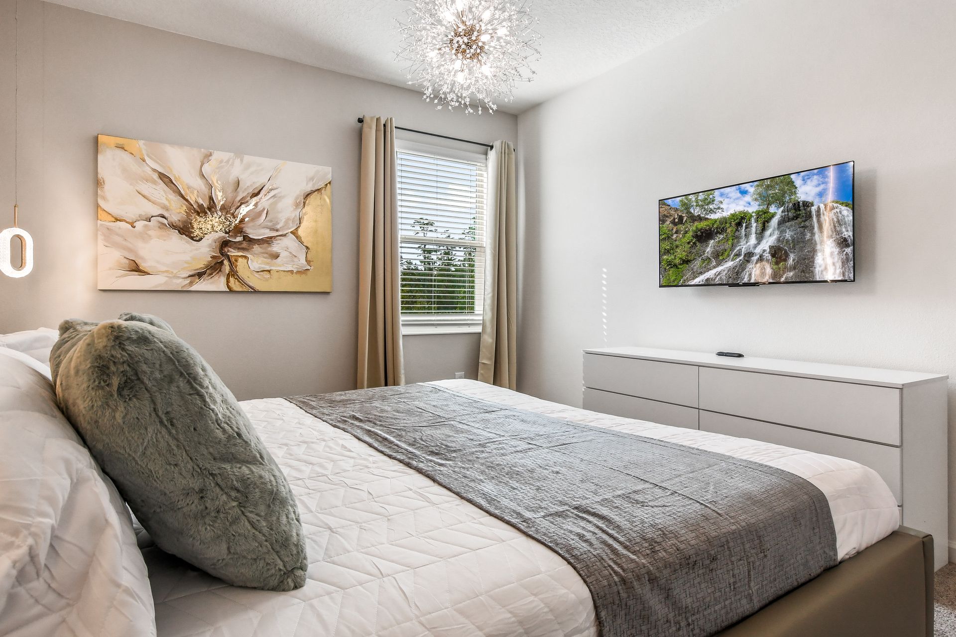 Tranquil bedroom with soft textures, floral artwork, modern lighting, and serene decor.