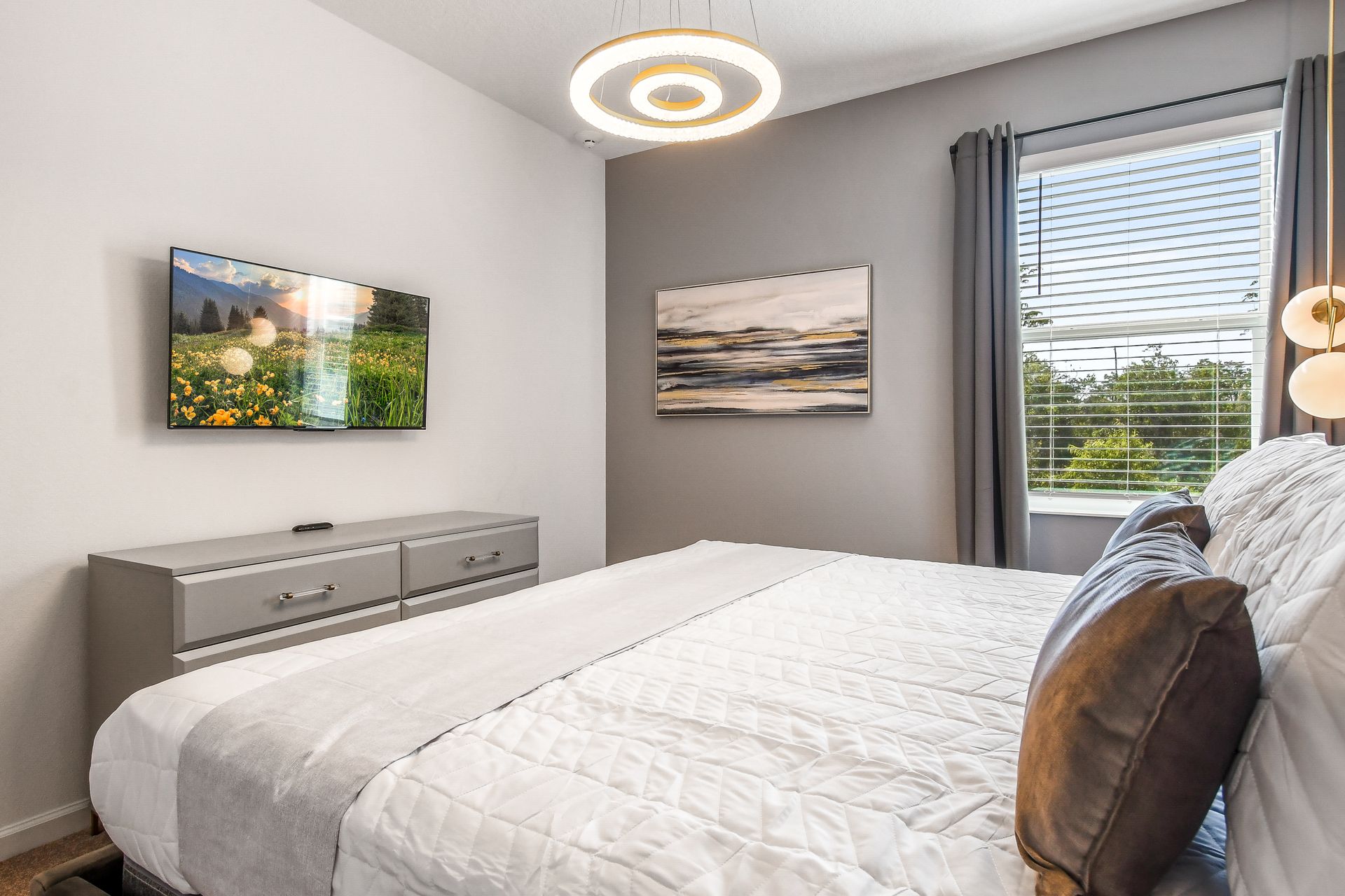 Serene bedroom with modern lighting, a cozy bed, and scenic artwork on the walls.
