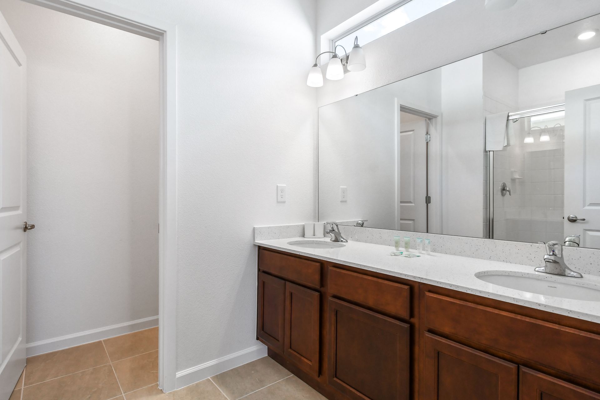 Spacious bathroom featuring double sinks, quartz countertops, and a walk-in shower.