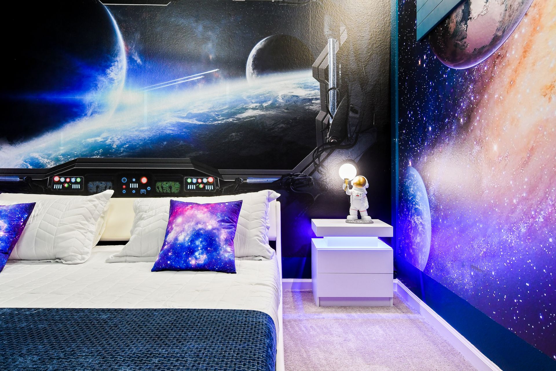 Astronaut-inspired space bedroom featuring galaxy pillows, glowing decor, and cosmic murals.