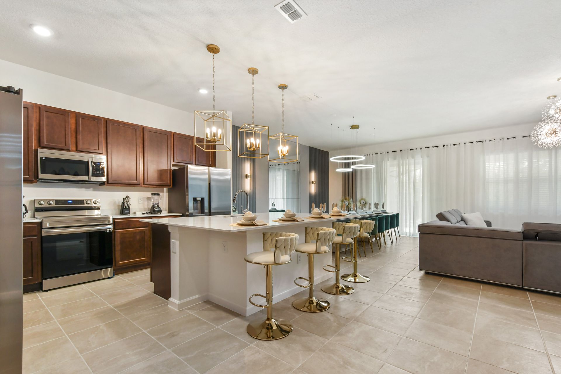 Chef’s kitchen with island seating, gold lighting, and seamless open layout.
