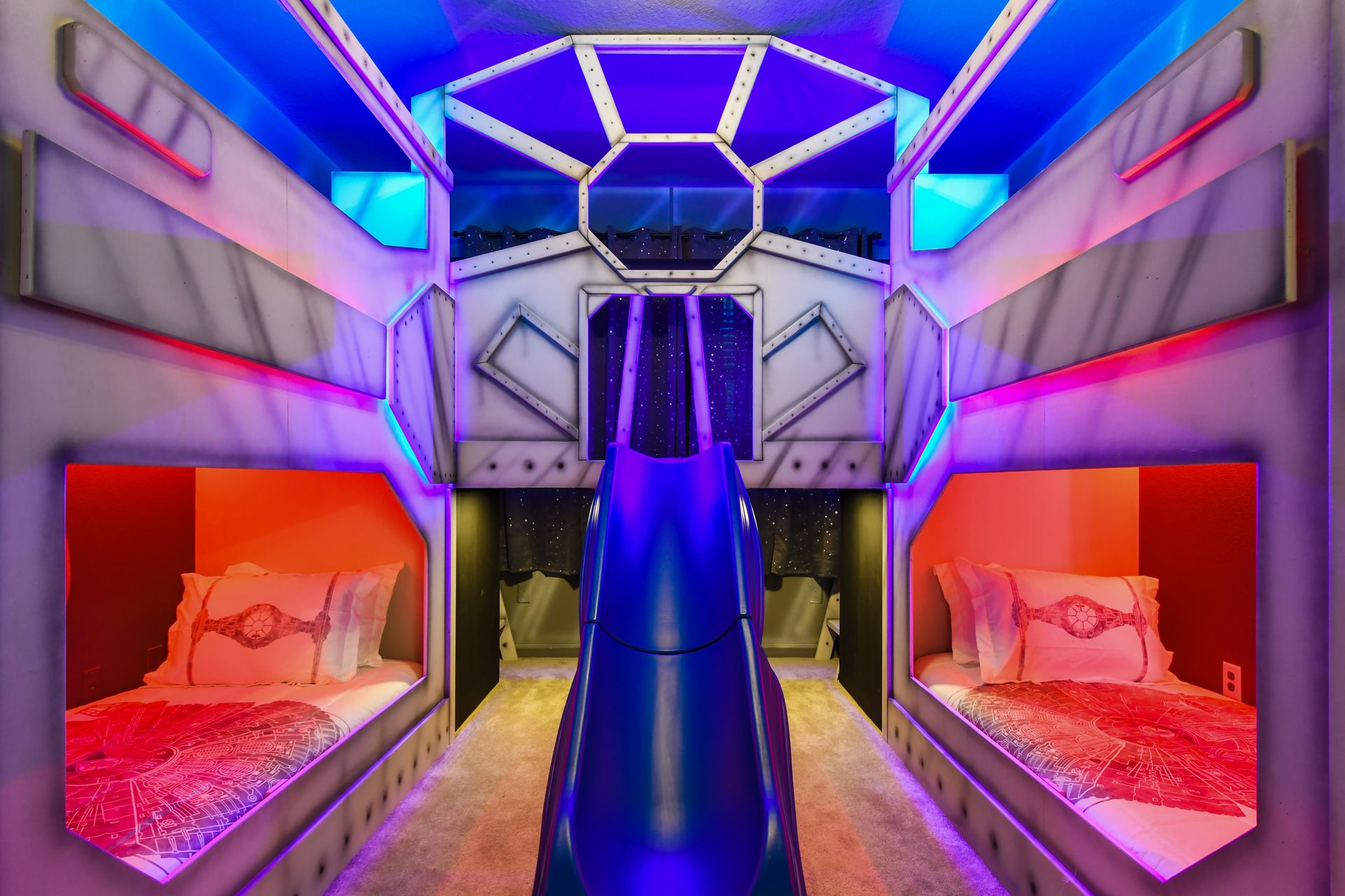 Epic galaxy-themed kids’ room with custom bunk beds, slide, and starry lights.
