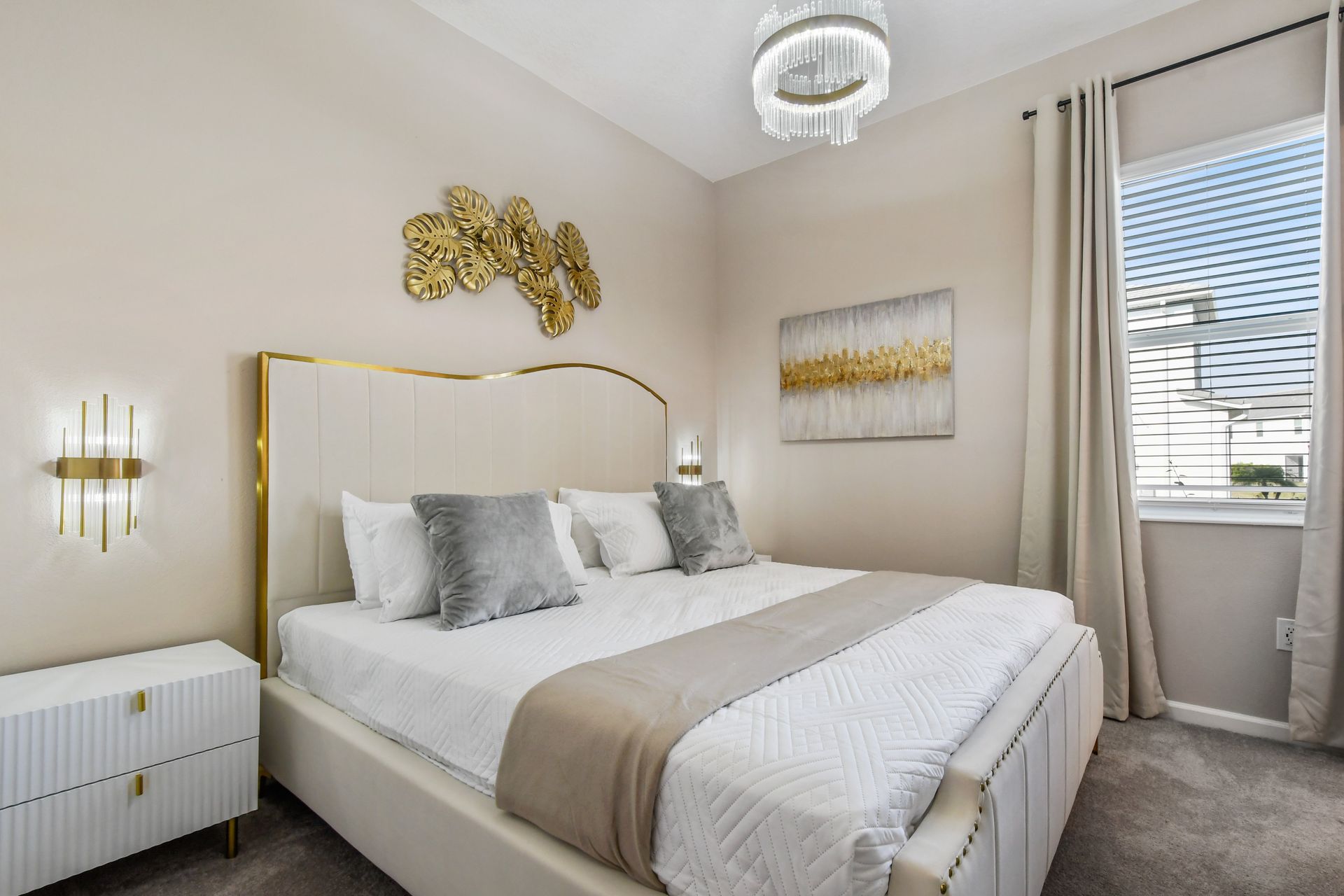 Relax in a luxe bedroom with plush bedding, gold accents, and natural light.
