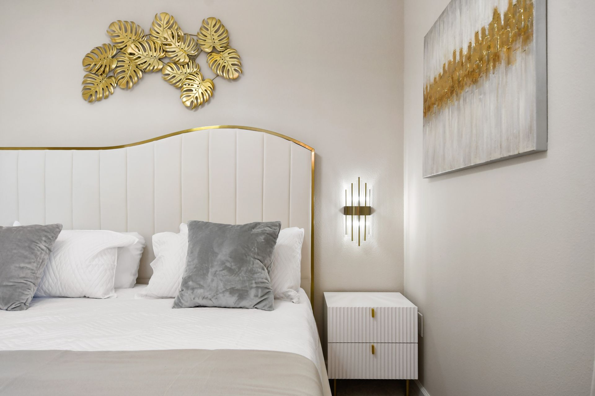 Relax in a luxe bedroom with plush bedding, gold accents, and natural light.
