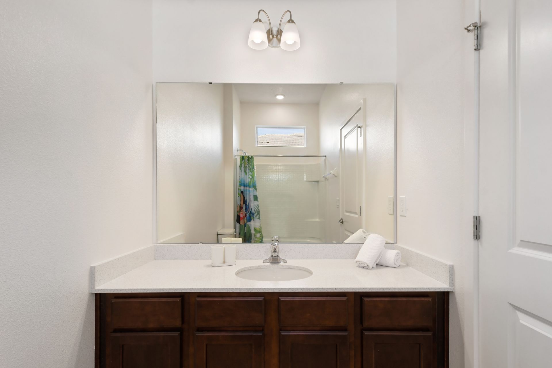 Bright and simple bathroom with tropical shower curtain and clean modern finish.
