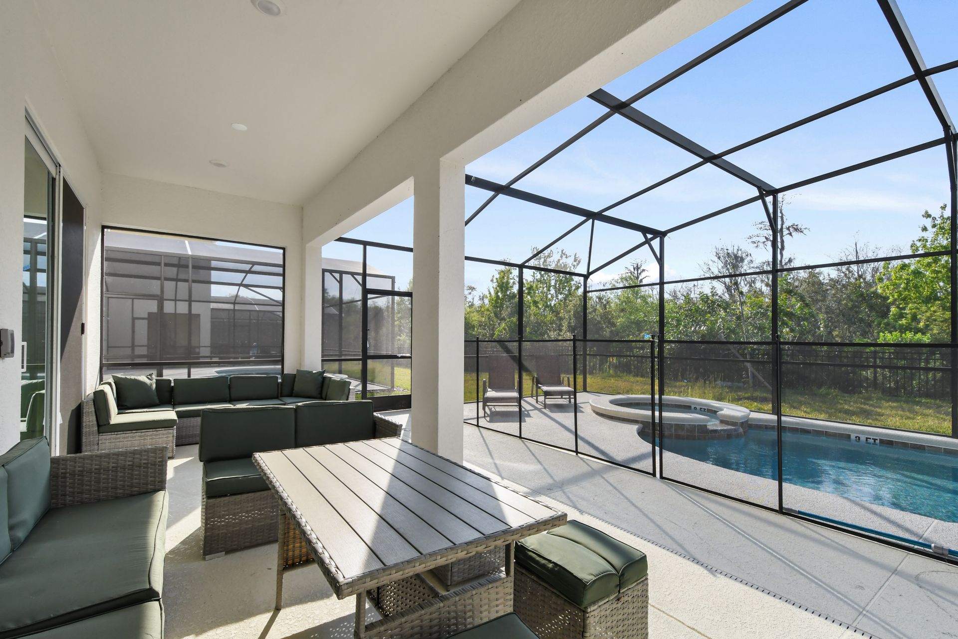 Spacious screened patio with dining, lounge seating, and private pool view.
