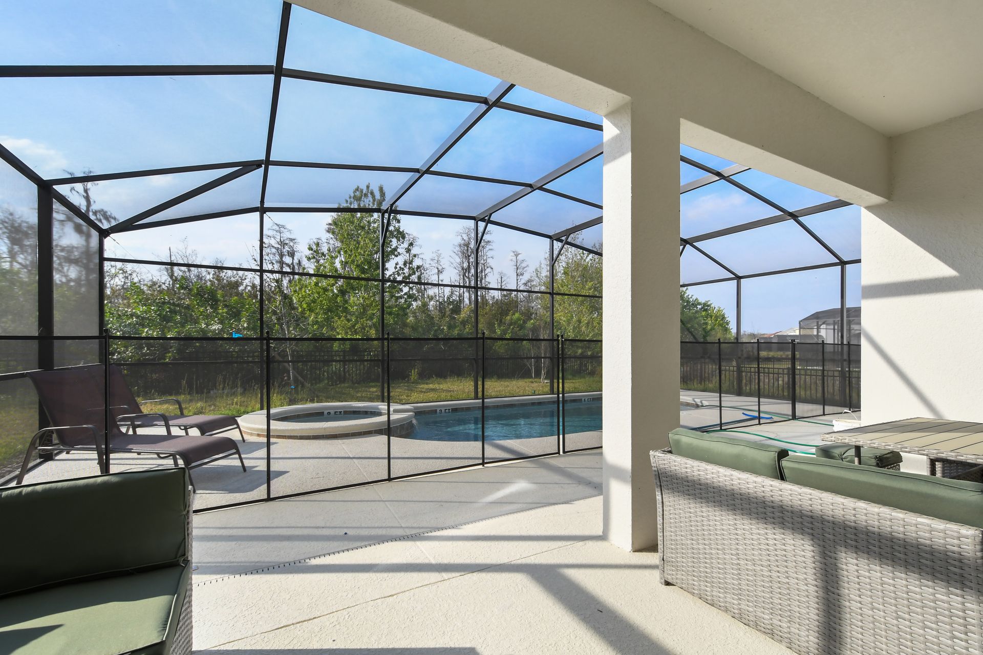 Spacious screened patio with dining, lounge seating, and private pool view.
