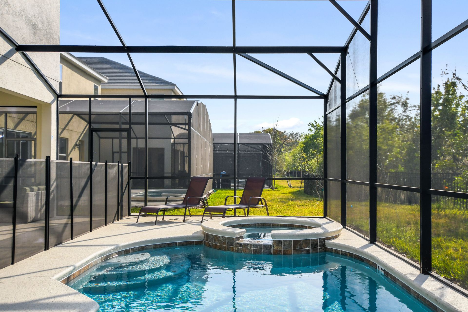 Private screened pool and spa with lounge chairs and shaded patio seating.
