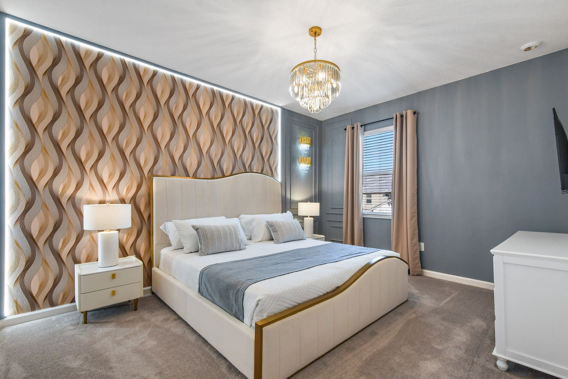 Chic bedroom with statement wall, plush king bed, and sparkling chandelier.
