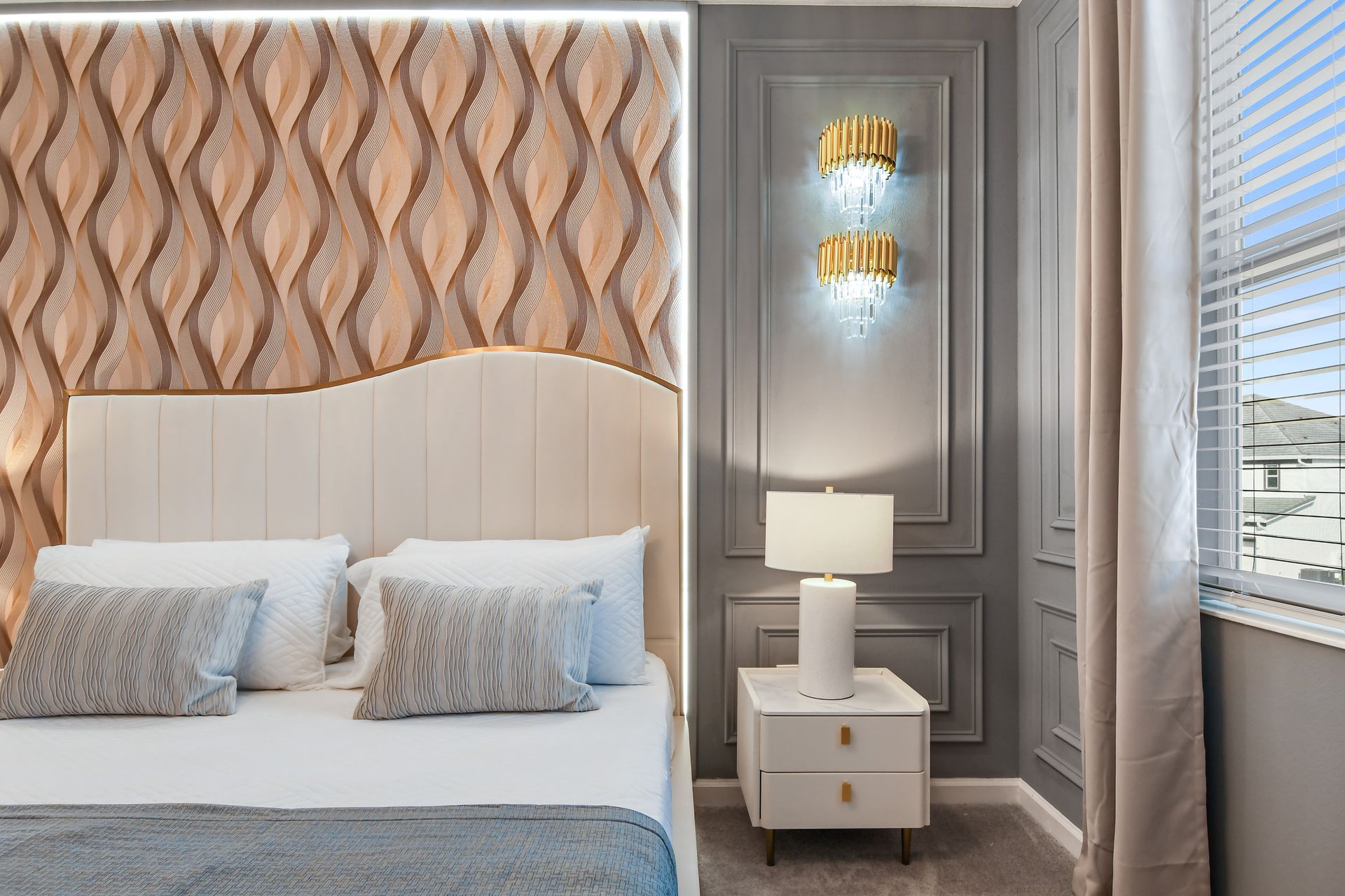 Chic bedroom with statement wall, plush king bed, and sparkling chandelier.
