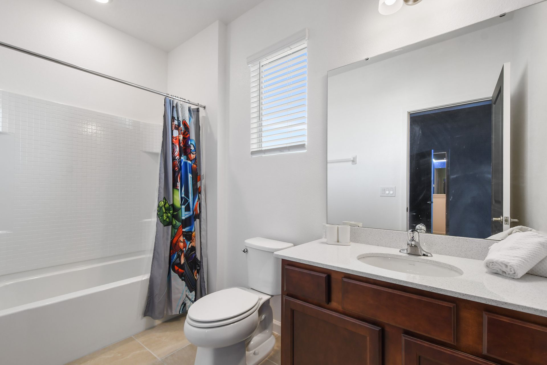 Bright and clean bathroom with a fun superhero shower curtain for the kids.
