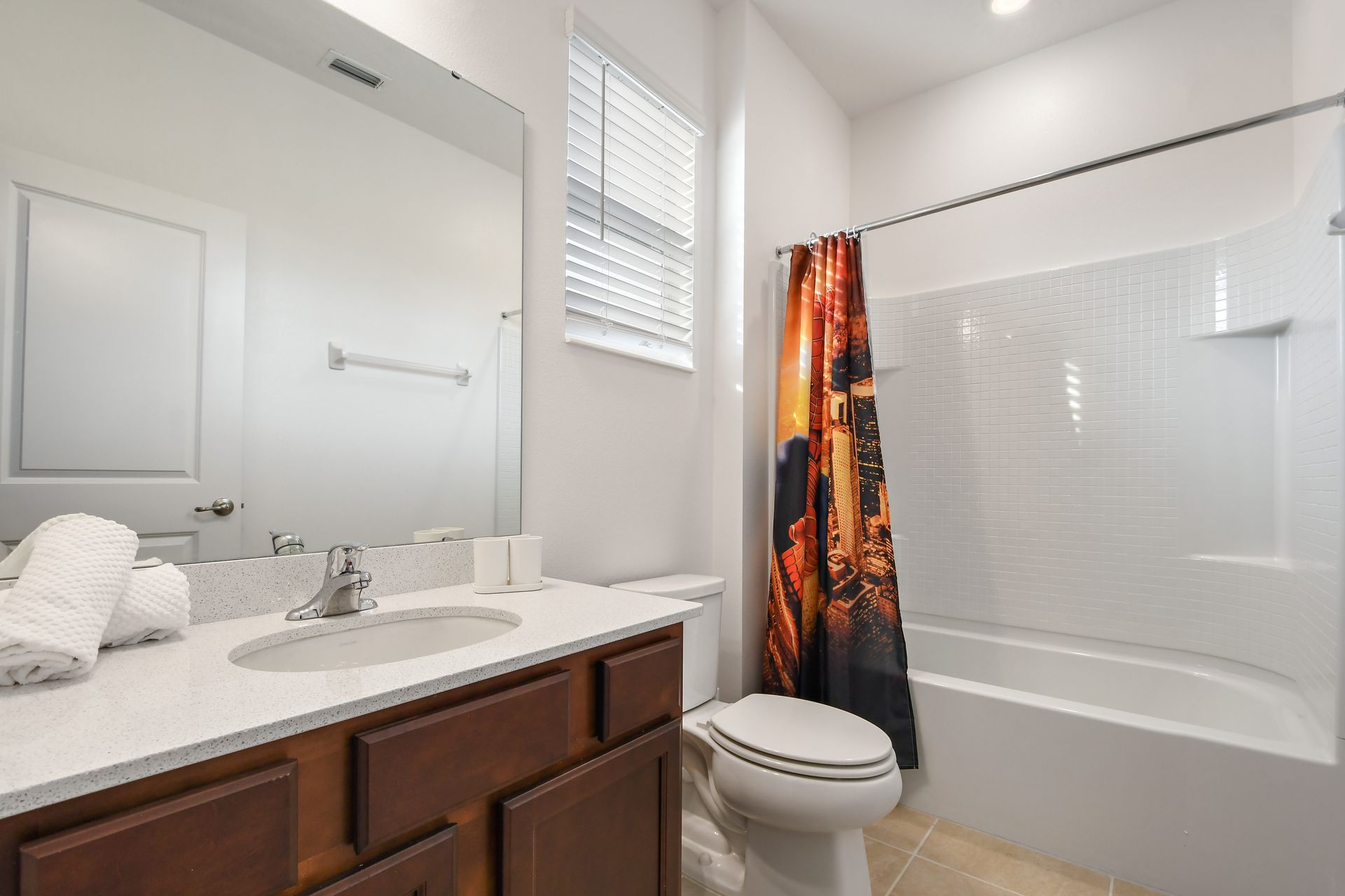 Modern bathroom featuring a vibrant cityscape shower curtain, sleek white countertops