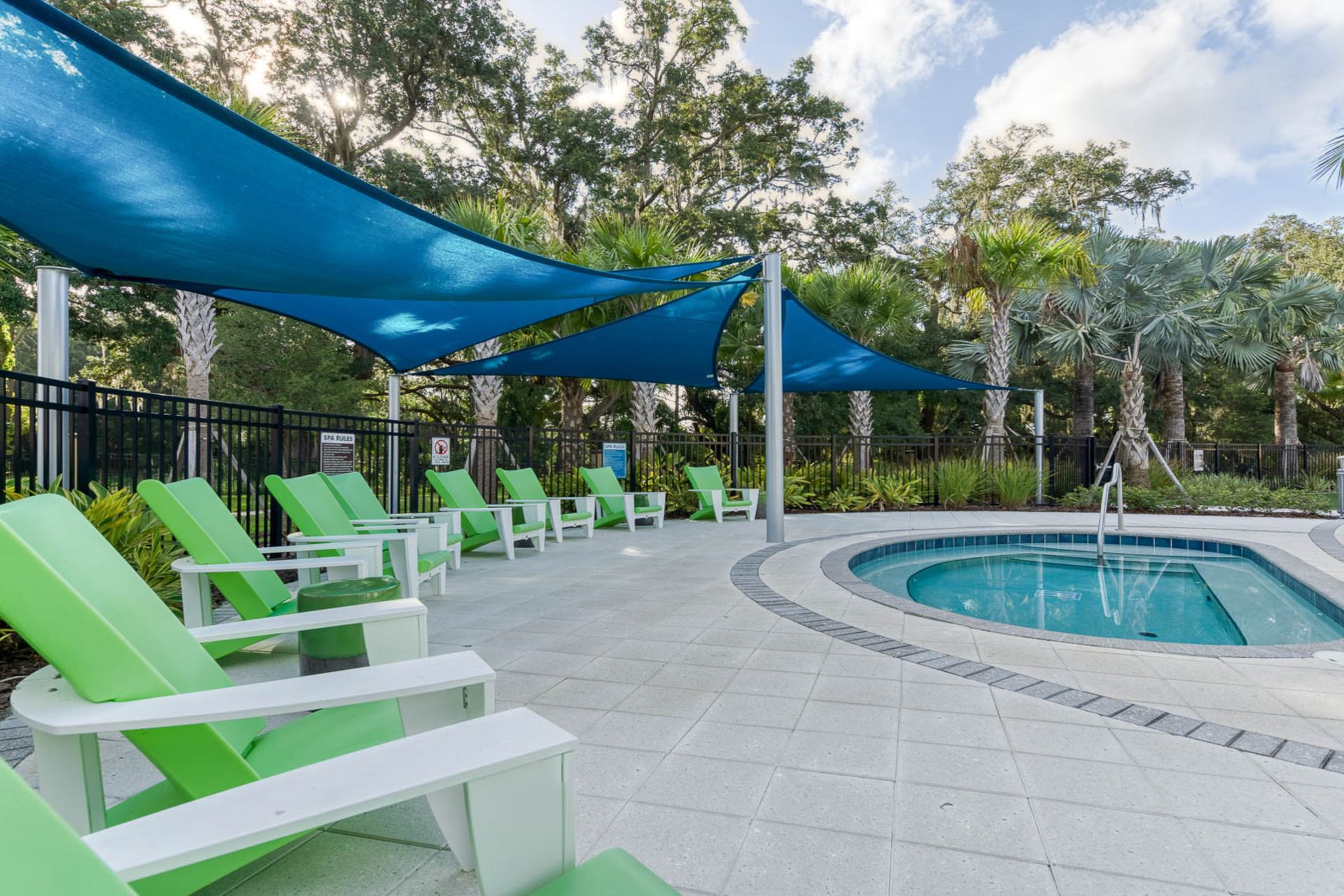 Unwind in a shaded lounge by the spa, surrounded by lush palms and serene vibes