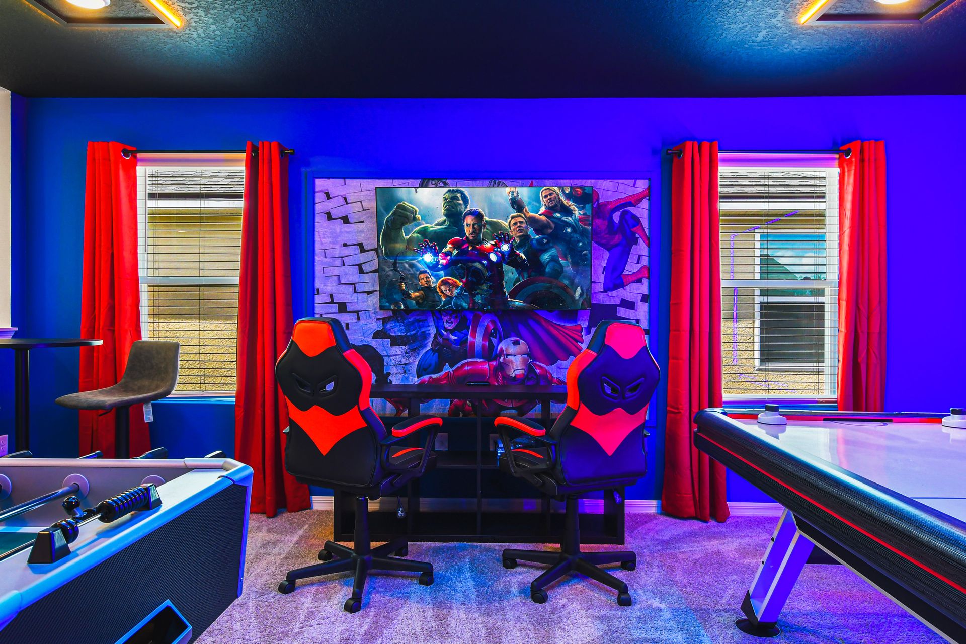 Epic Avengers-themed game zone with foosball, air hockey, and gaming setup.