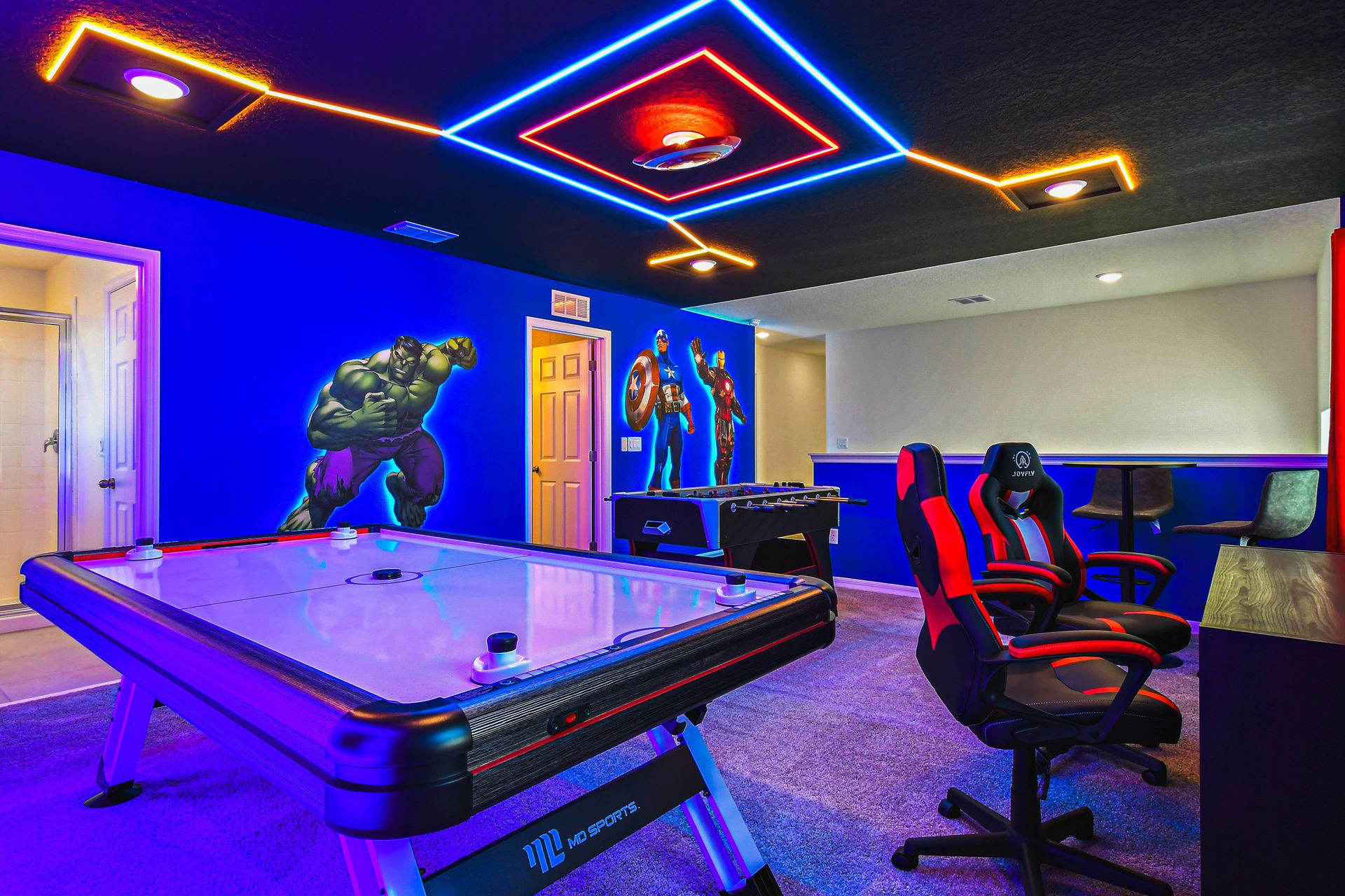 Ultimate Avengers arcade with foosball, air hockey, gaming chairs, and neon glow.