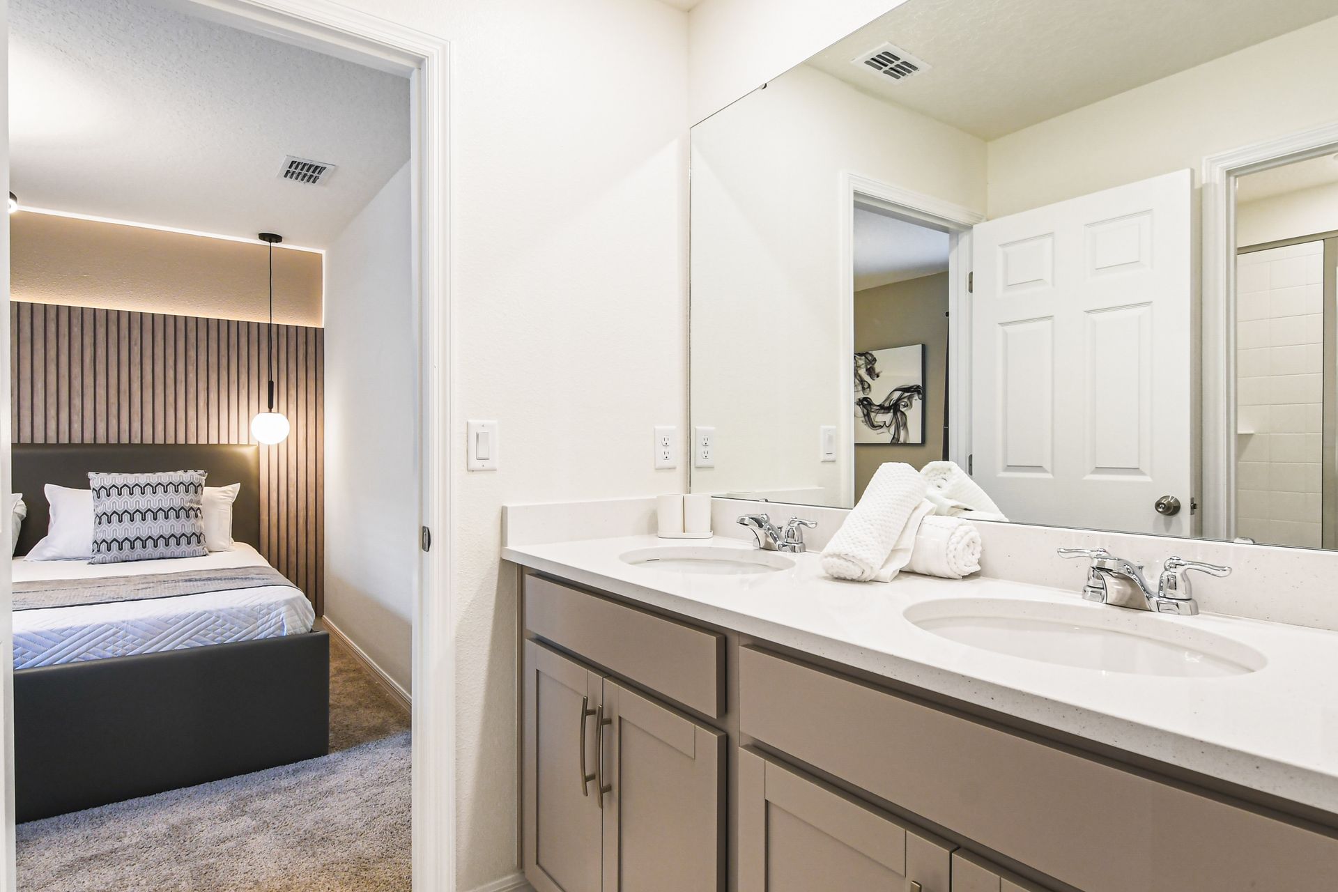 Elegant bathroom with dual sinks, walk-in shower, and access to modern king bedroom.