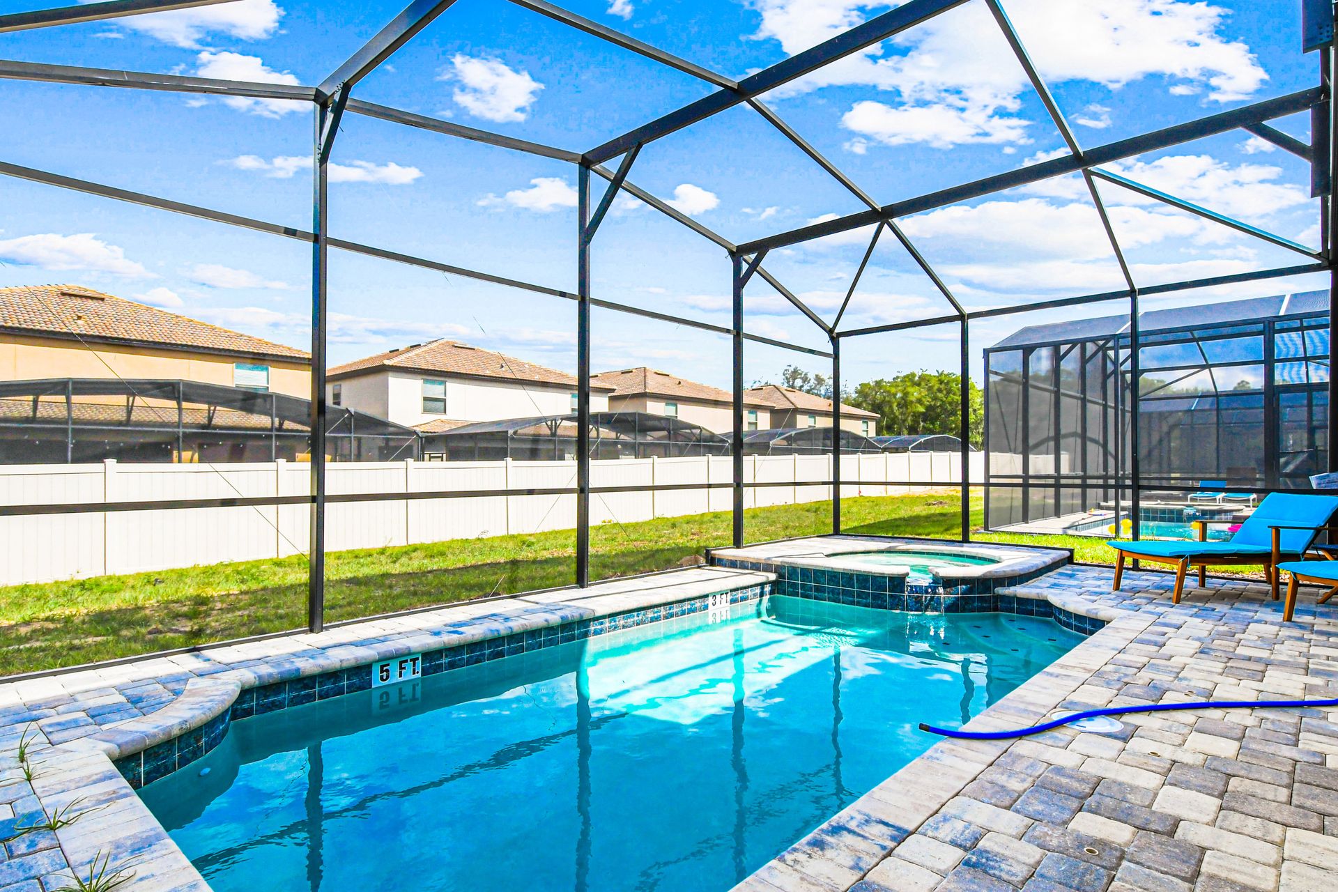 Screened-in pool and spa with lounge chairs, sunny views, and paved deck.