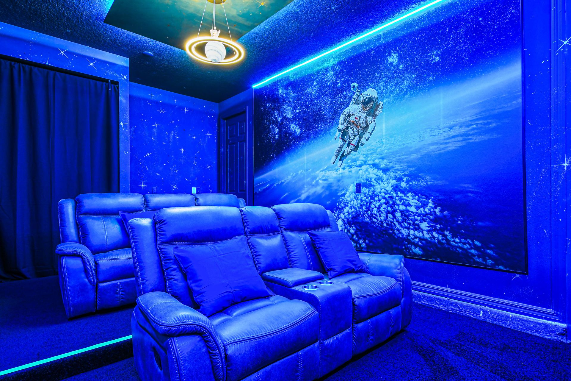 Space-themed home theater with recliners, starry walls, and ambient lighting.