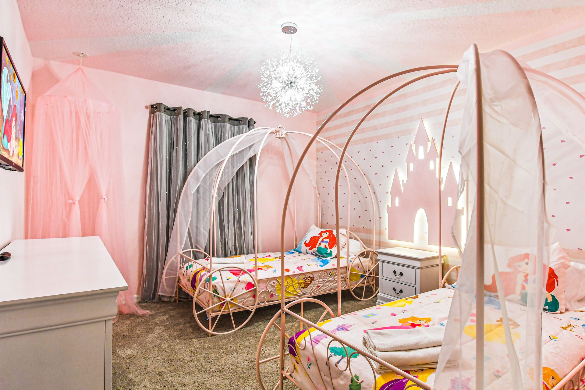 Fairy tale-themed bedroom with carriage beds, soft pink decor, and castle lighting.