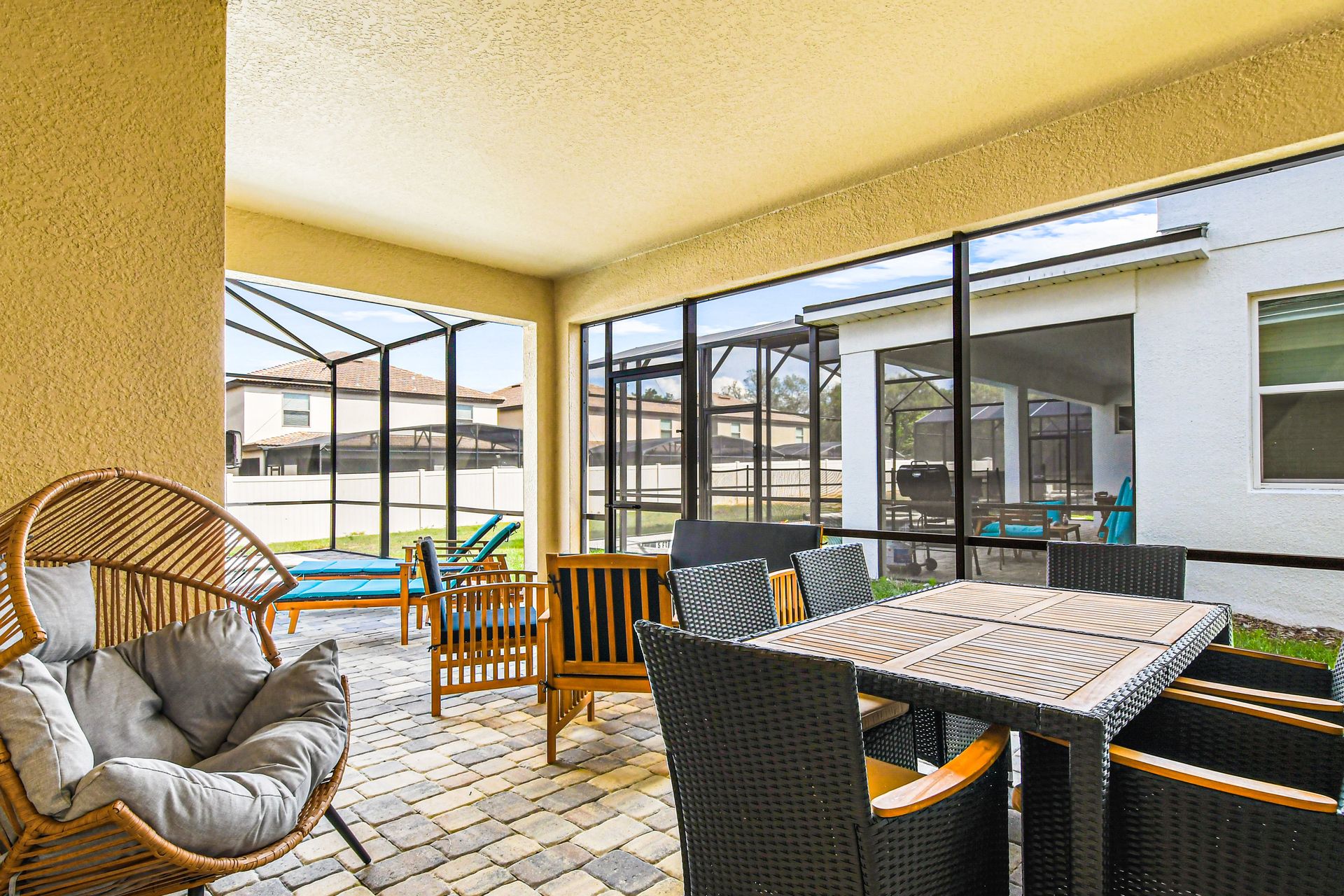 Screened patio with cozy seating, dining area, and poolside views.