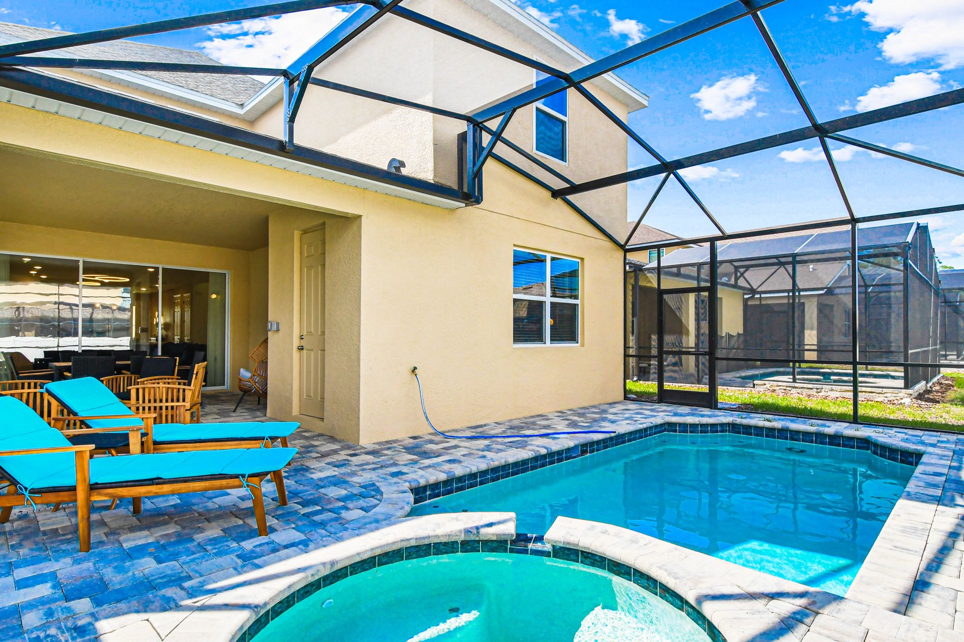 Screened pool and spa with lounge chairs, patio seating, and sunny views.