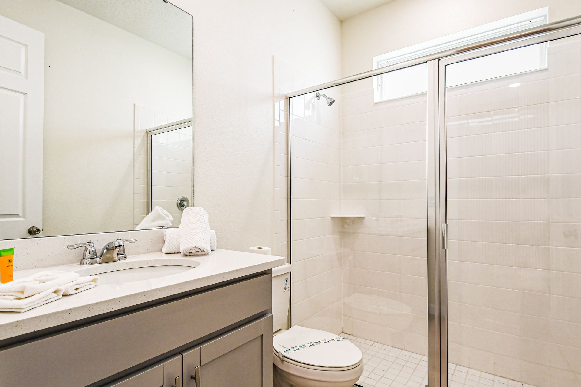 Modern bathroom with glass shower, sleek vanity, and bright lighting.