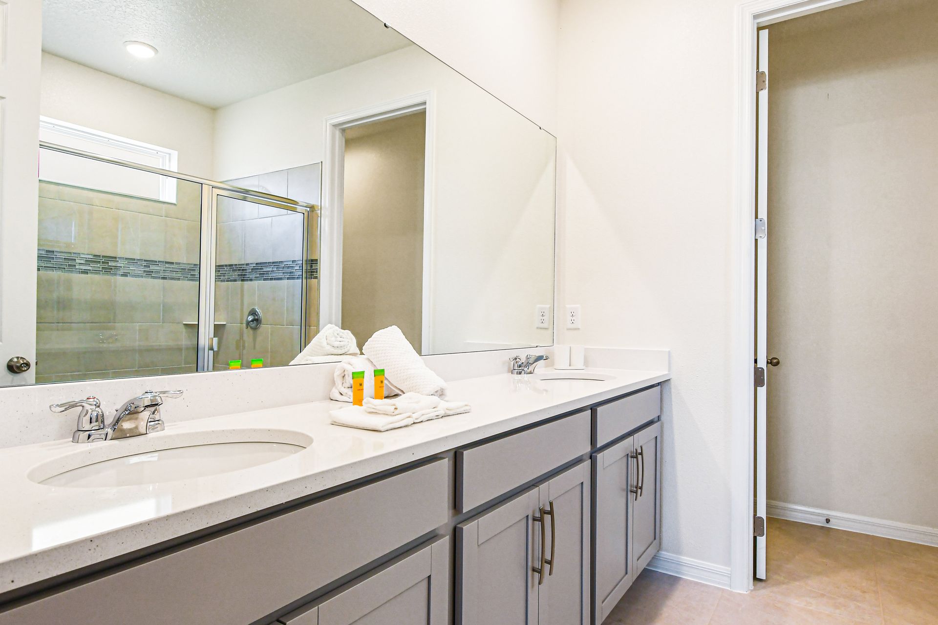 Spacious bathroom with dual sinks, glass shower, and sleek modern design.