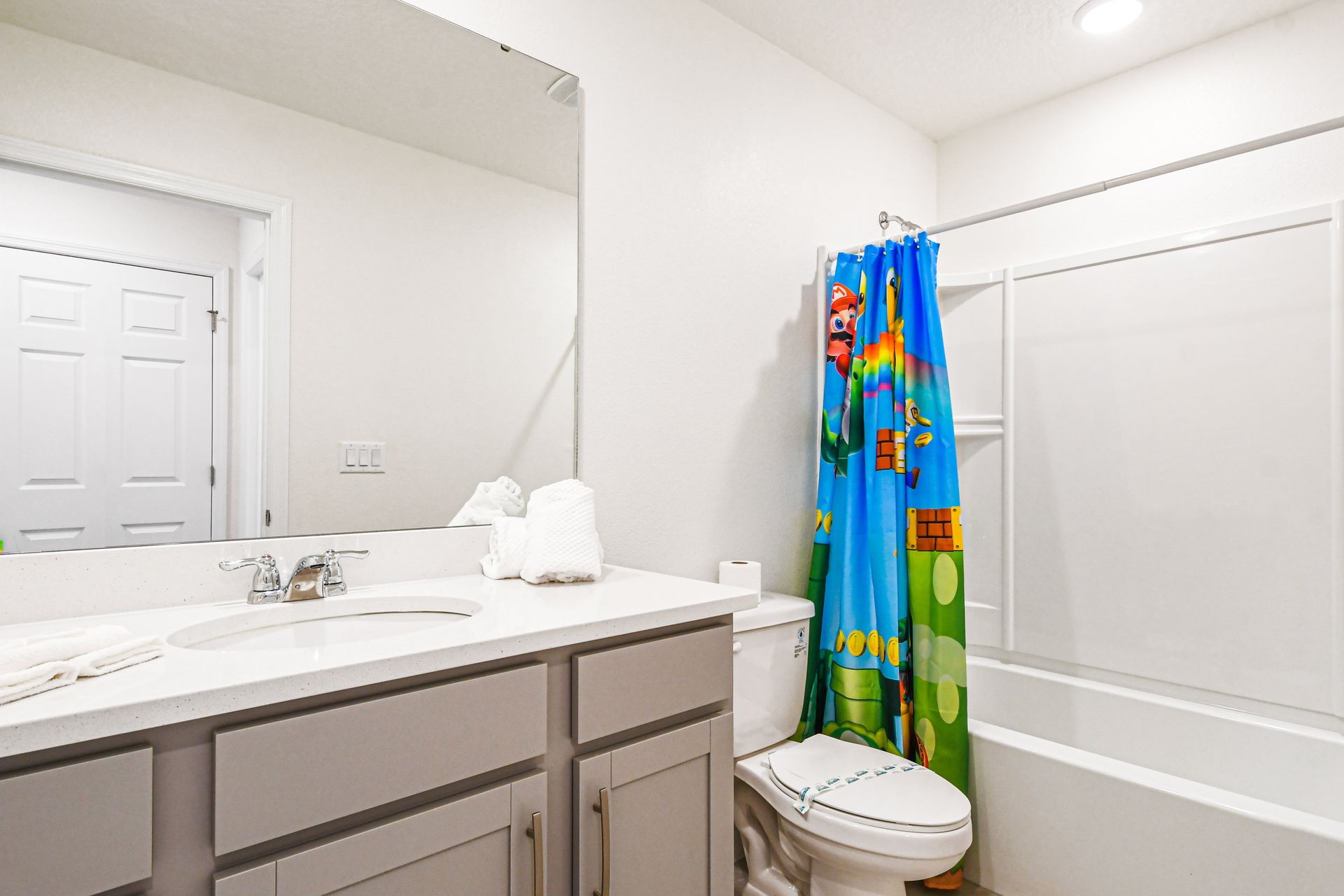 Fun bathroom with Mario-themed shower curtain, modern vanity, and bright lighting.