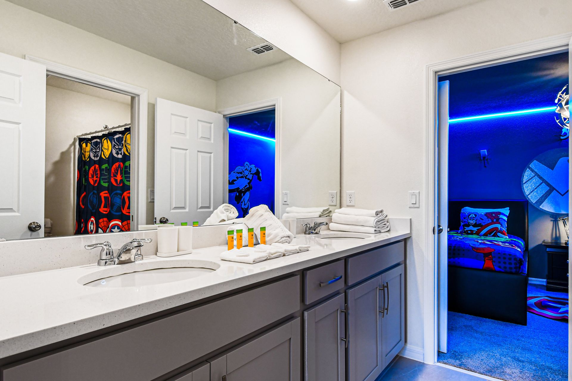 Spacious bathroom with dual sinks, themed decor, and bright modern lighting.