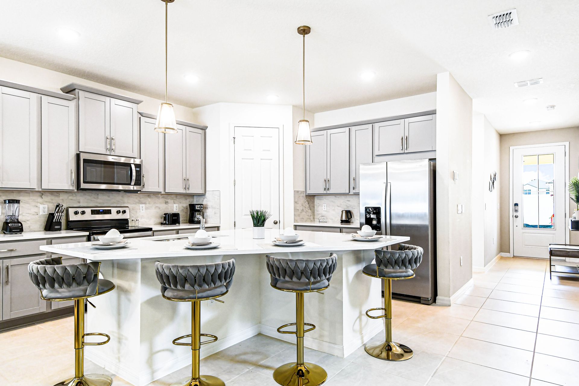 Modern kitchen with gray cabinets, island seating, and stainless steel appliances.