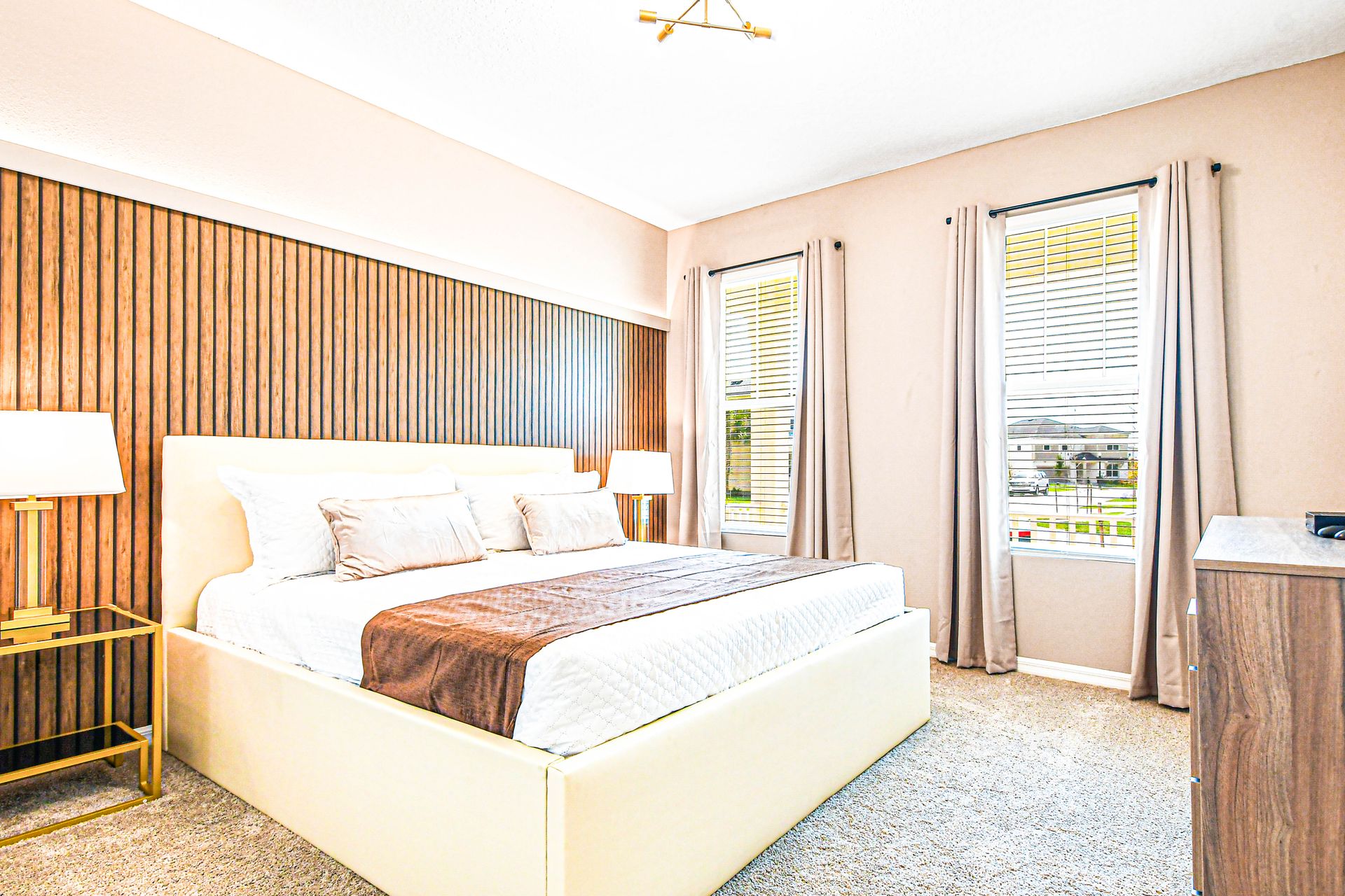 Bright bedroom with wood accent wall, cozy bedding, and natural light.