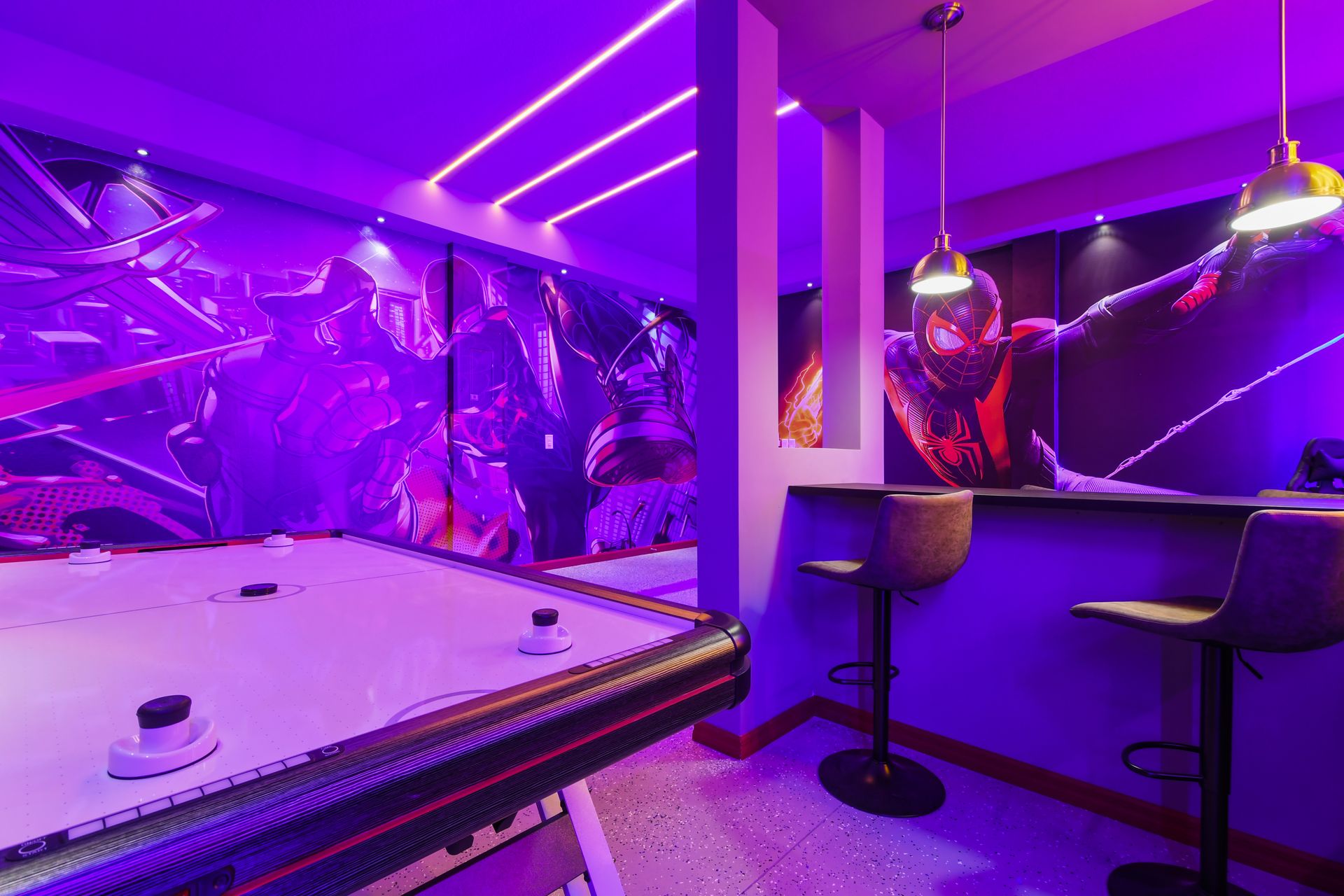 Comic-themed game room with neon lights, air hockey, and bar seating for fun.
