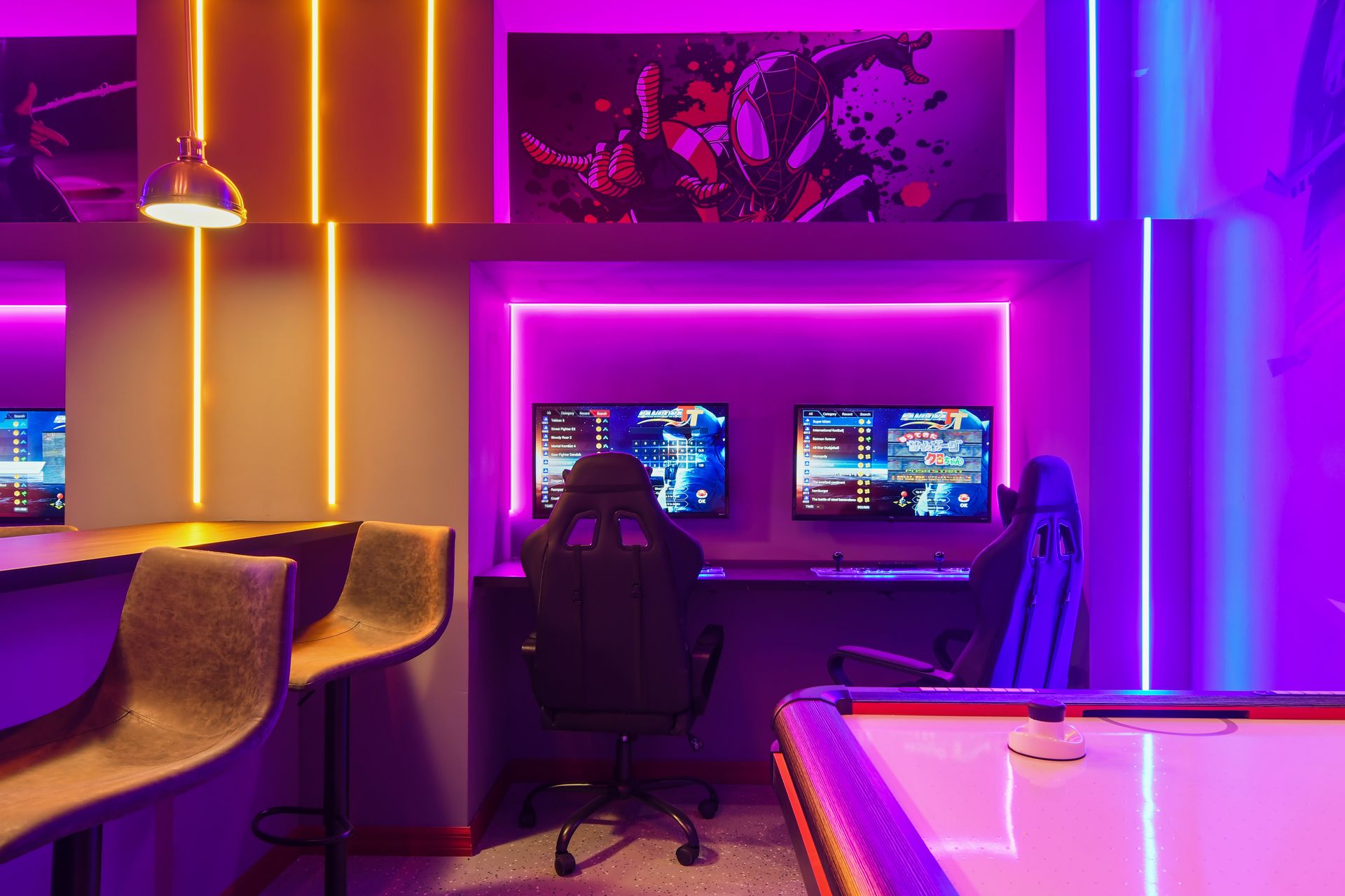 Neon-lit gaming lounge with dual setups, bar seating, and arcade-style air hockey.