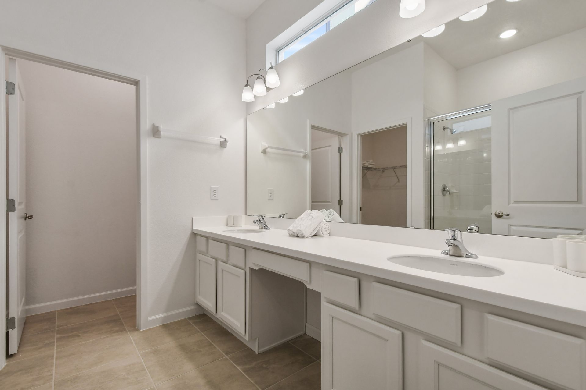 Spacious bathroom with double vanity, bright lighting, and modern fixtures.