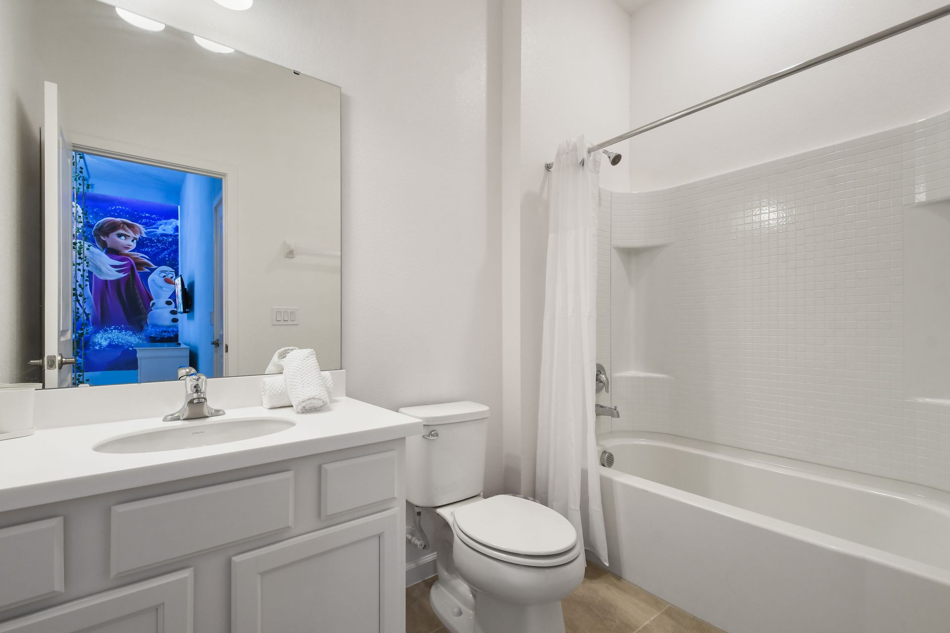 Bright and clean bathroom with a large mirror and a full shower-tub combo.