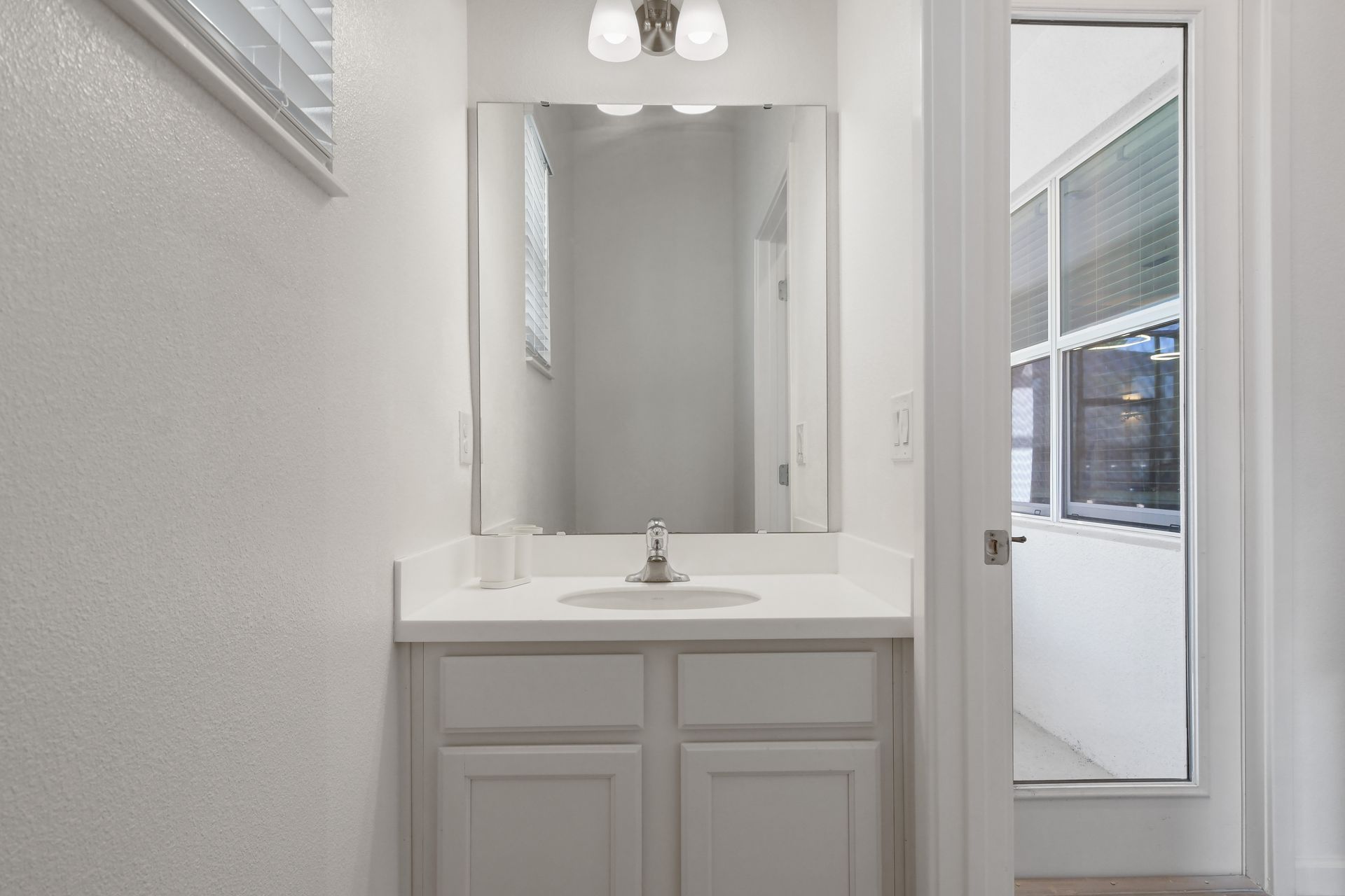 Bright and simple bathroom with natural light and a clean white vanity.