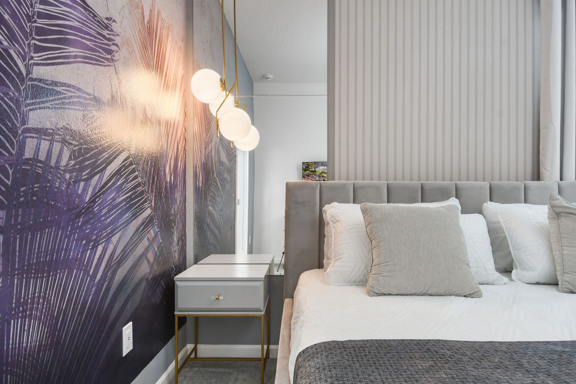 Modern bedroom with soft tones, palm accents, and elegant lighting for relaxation.