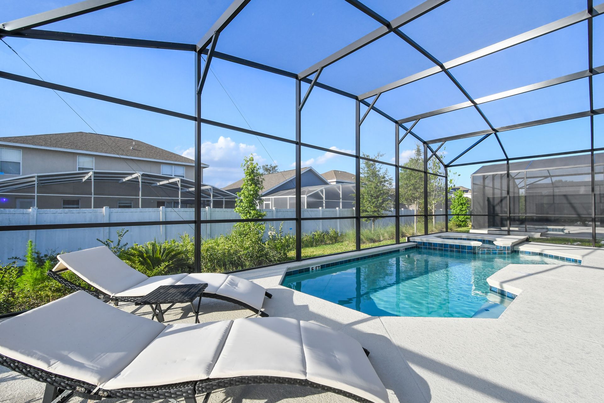 Screened-in pool area with lounge chairs, spa, and sunny views for relaxation.