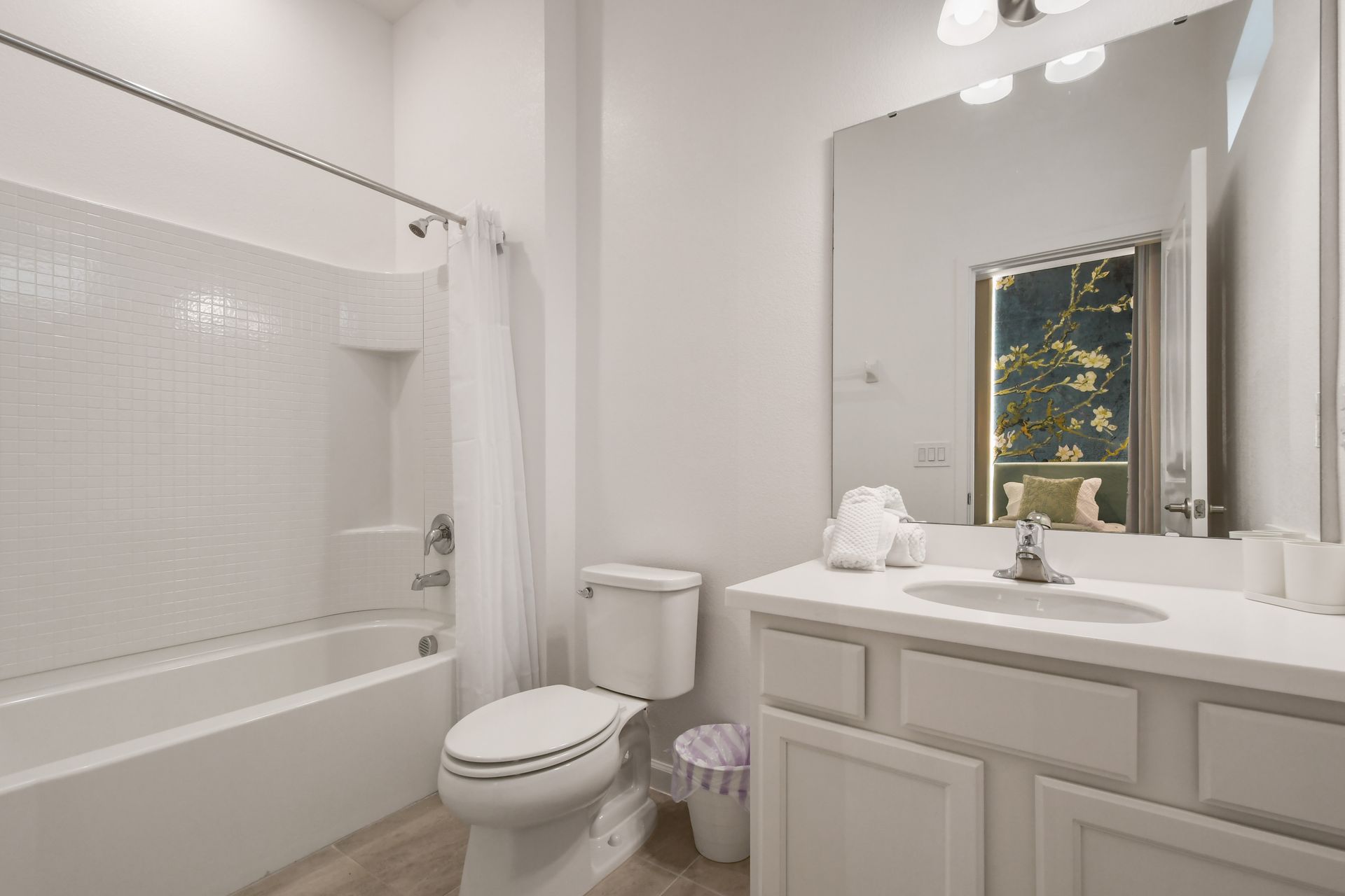 Bright and clean bathroom with a large mirror and a full shower-tub combo.