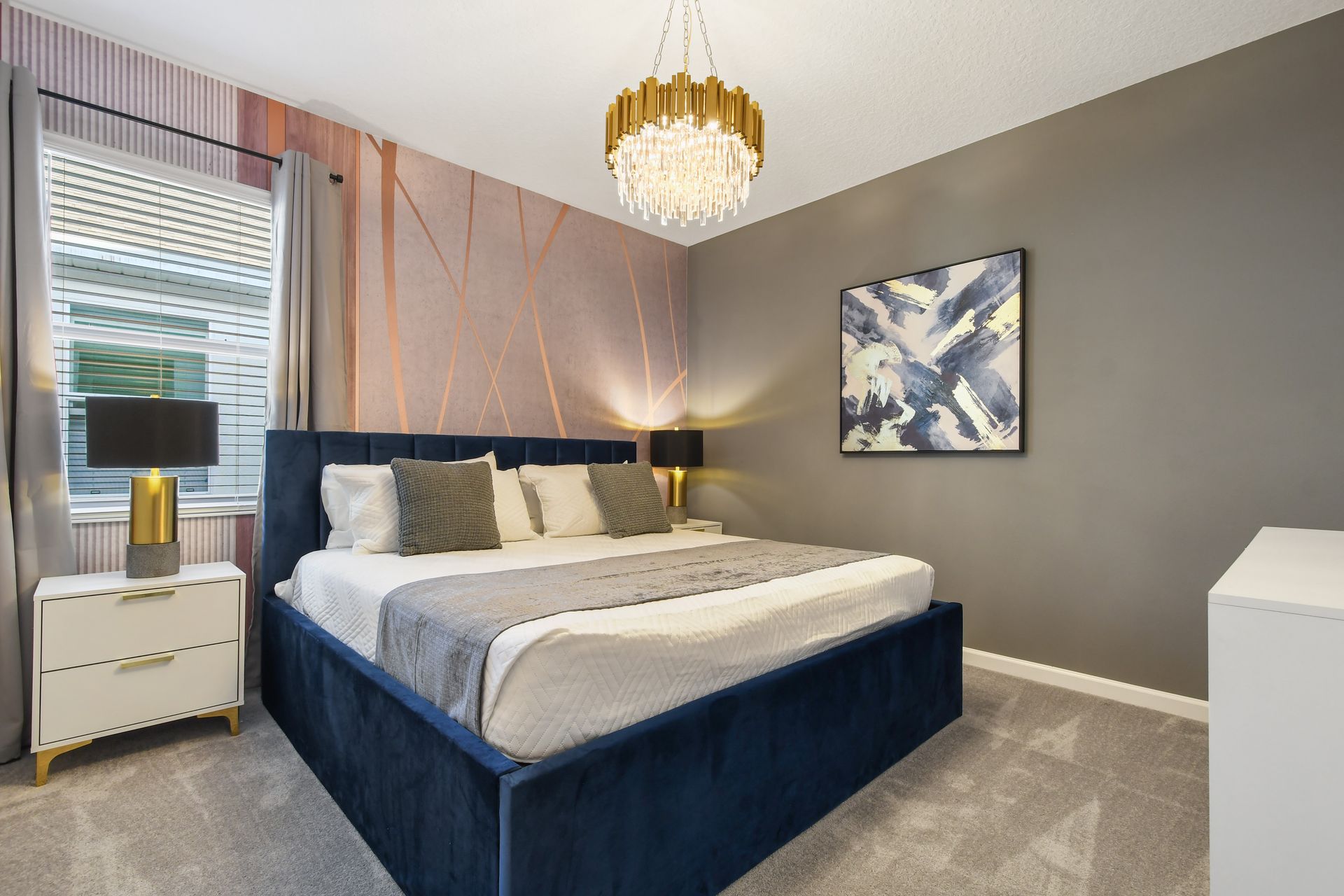 Elegant bedroom with modern accents, plush bedding, and a crystal chandelier.