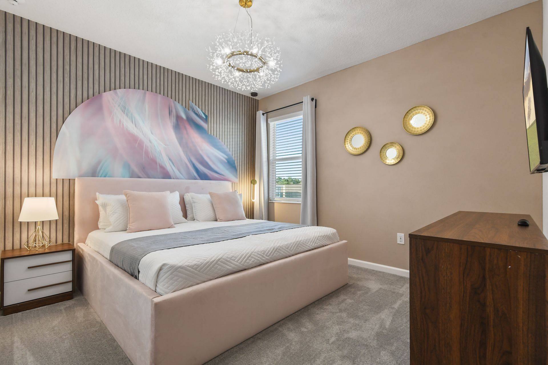Chic bedroom with soft pastels, modern decor, and a statement chandelier.