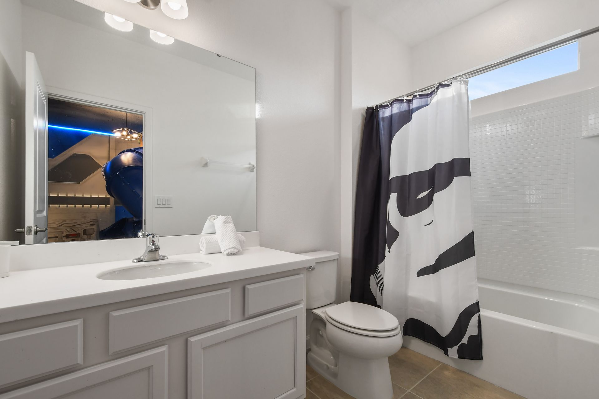Bright and clean bathroom with a large mirror and a full shower-tub combo.