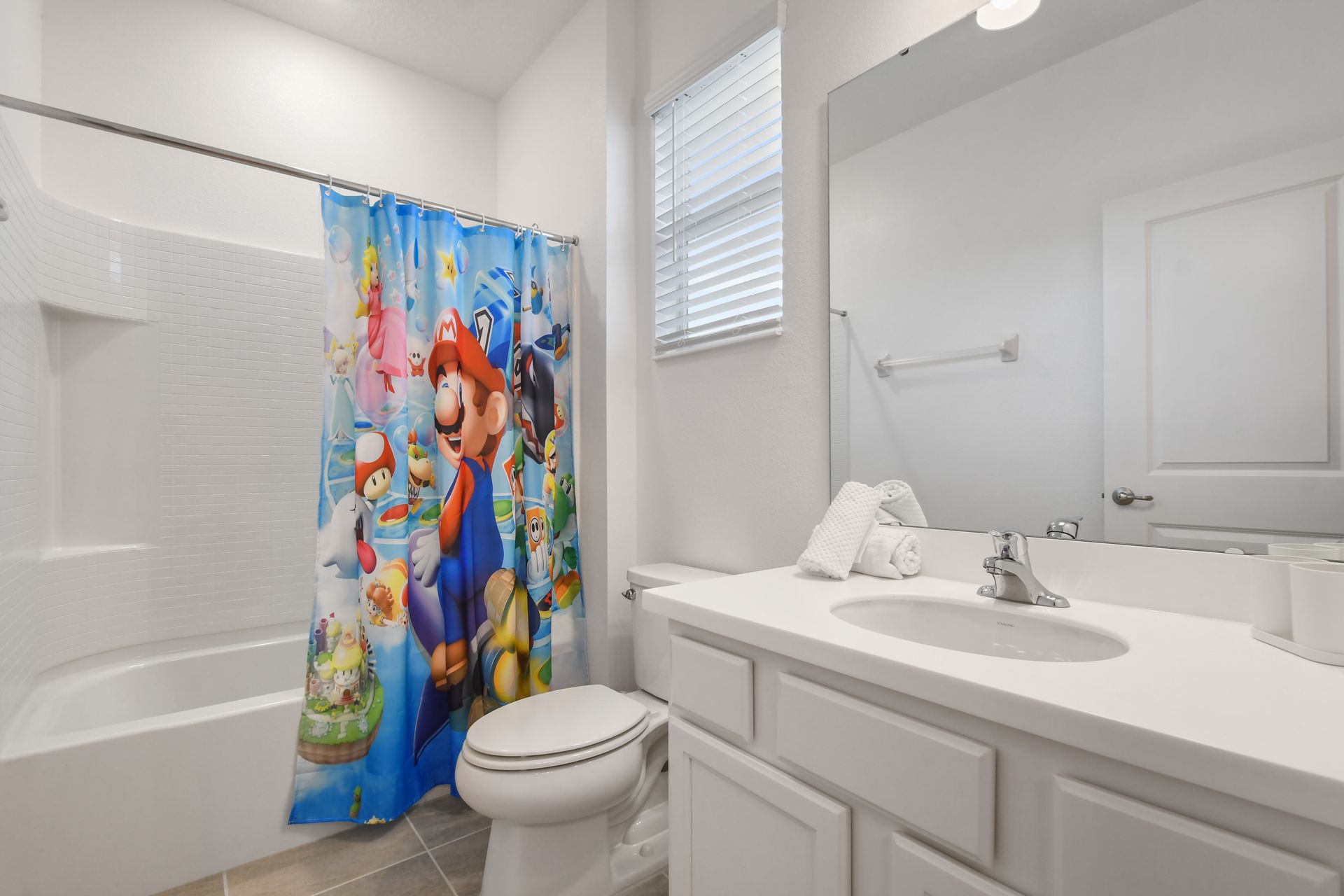 Bright and clean bathroom with a large mirror and a full shower-tub combo.