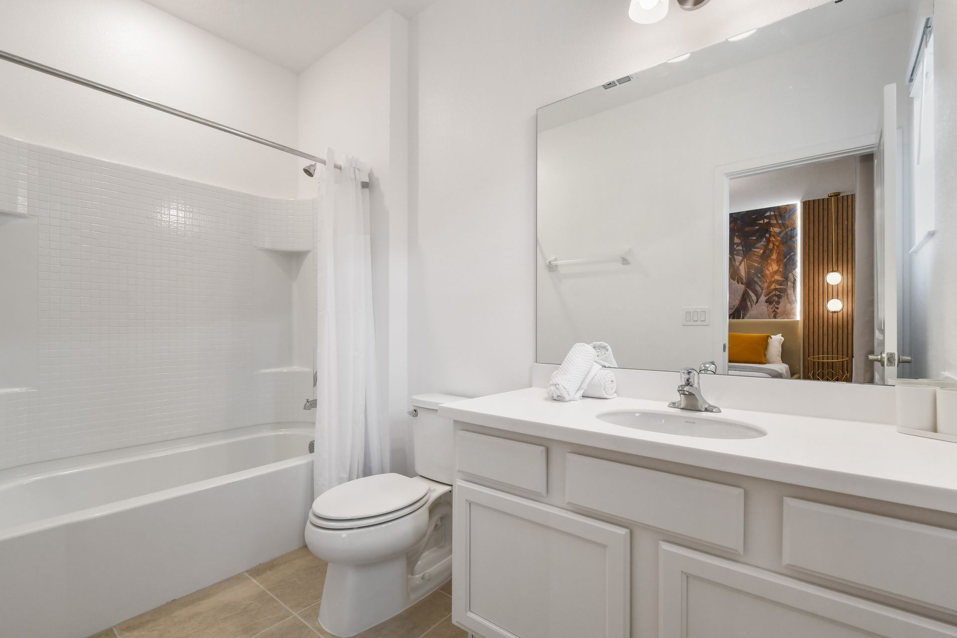 Bright and clean bathroom with a large mirror and a full shower-tub combo.