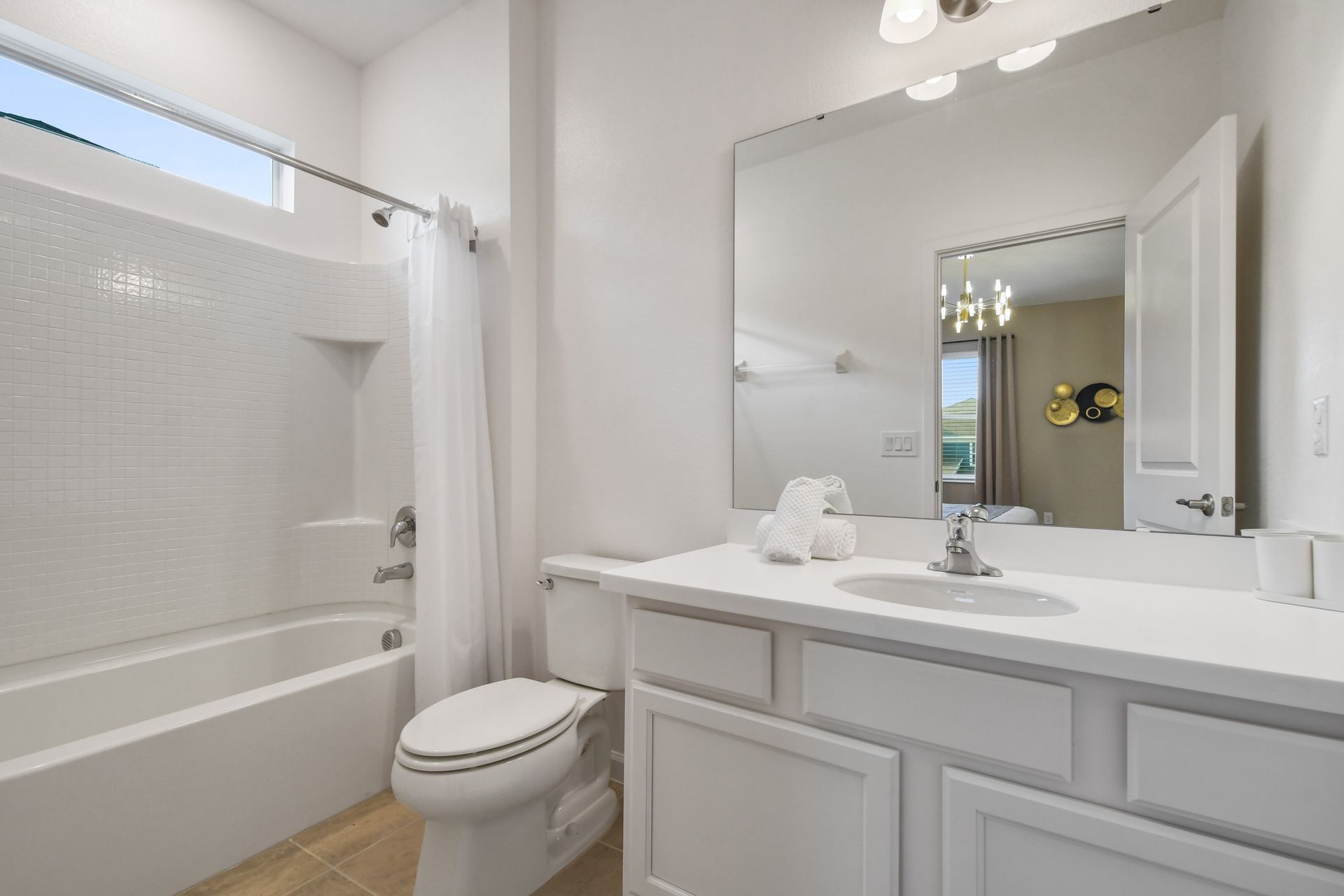 Bright and clean bathroom with a large mirror and a full shower-tub combo.