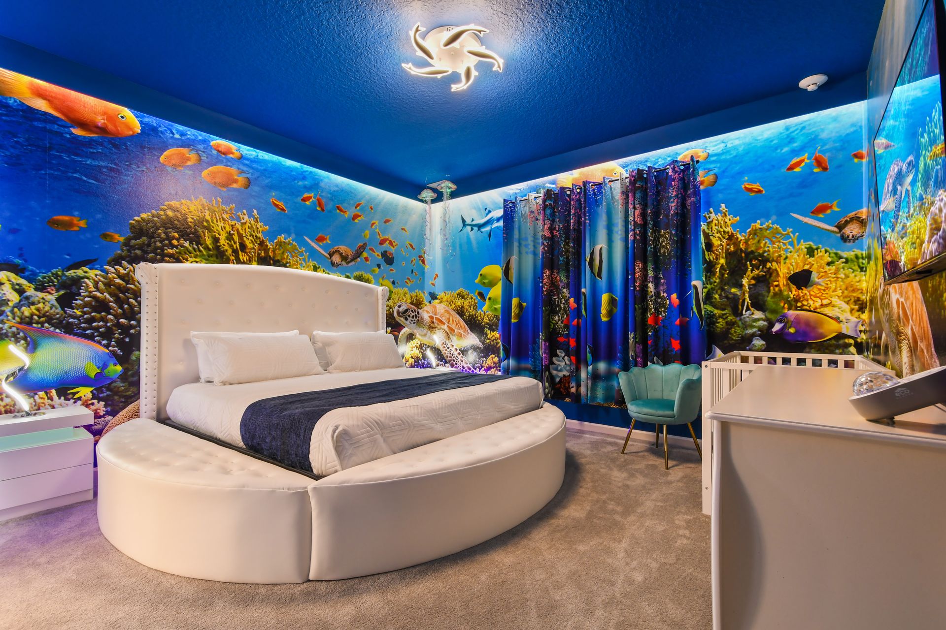 Underwater-themed room with vibrant murals, round bed, and ocean-inspired decor.