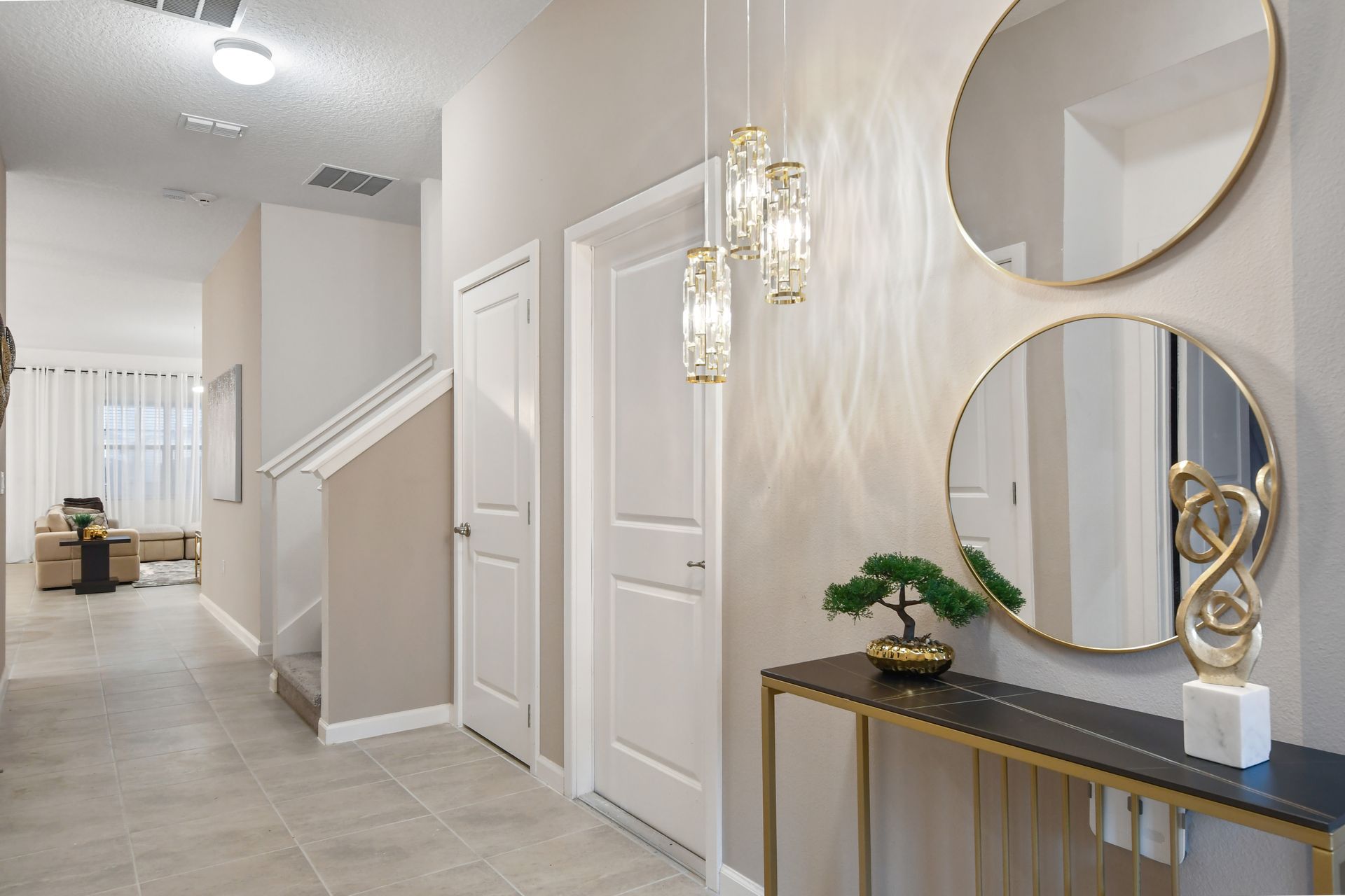 Stylish entryway with modern lighting, gold accents, and elegant wall mirrors
