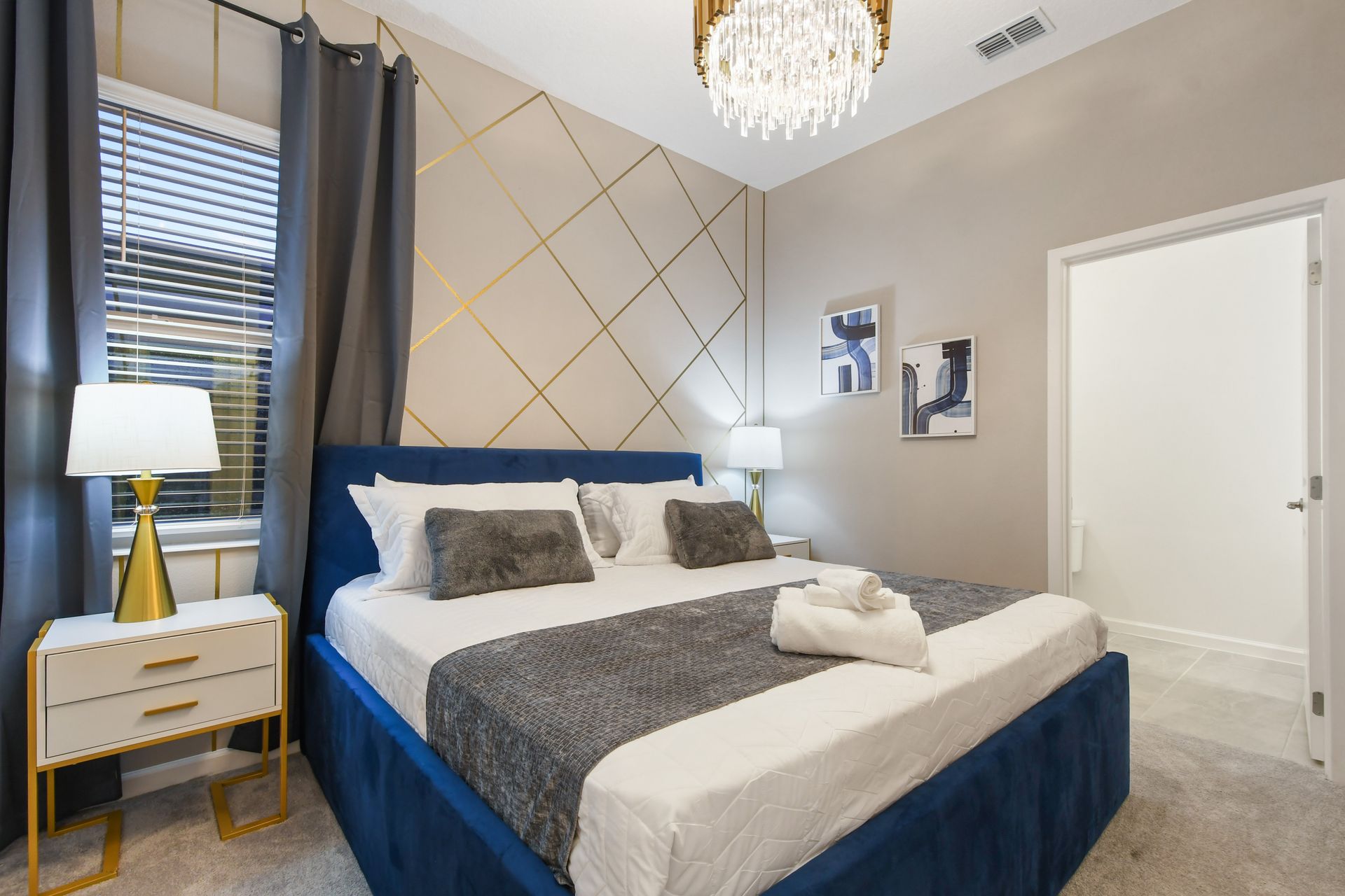 Elegant bedroom with luxe bedding, gold accents, and a stunning chandelier glow
