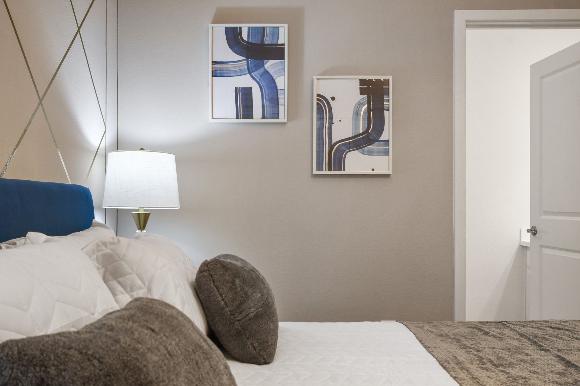 Cozy designer bedroom with plush pillows, modern art, and ambient lighting
